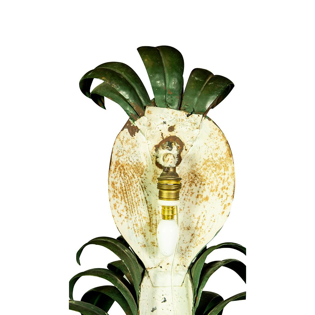 Pineapple finial with banana tree leaves in a red basket with scroll handles.