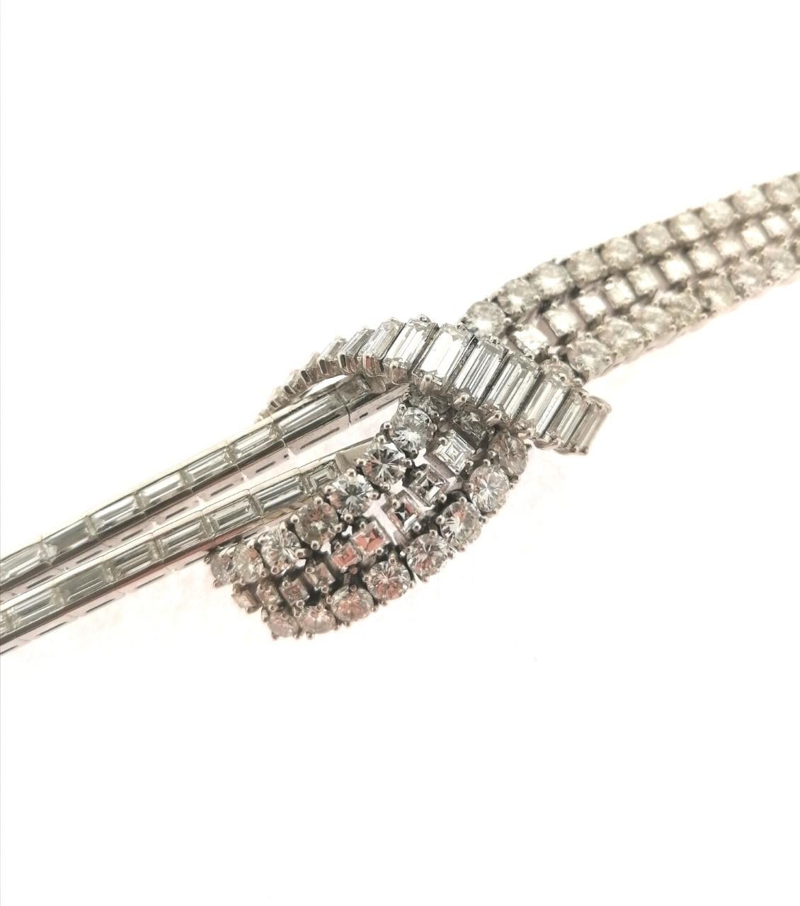 Magnificent Art Deco platinum bracelet with baguette, brilliant and carré cut diamonds. The calculated weight of the stones is 22 Carats. The jewelry craftsmanship to make the knot is very ingenious. Exceptional and delicate piece with a hundred
