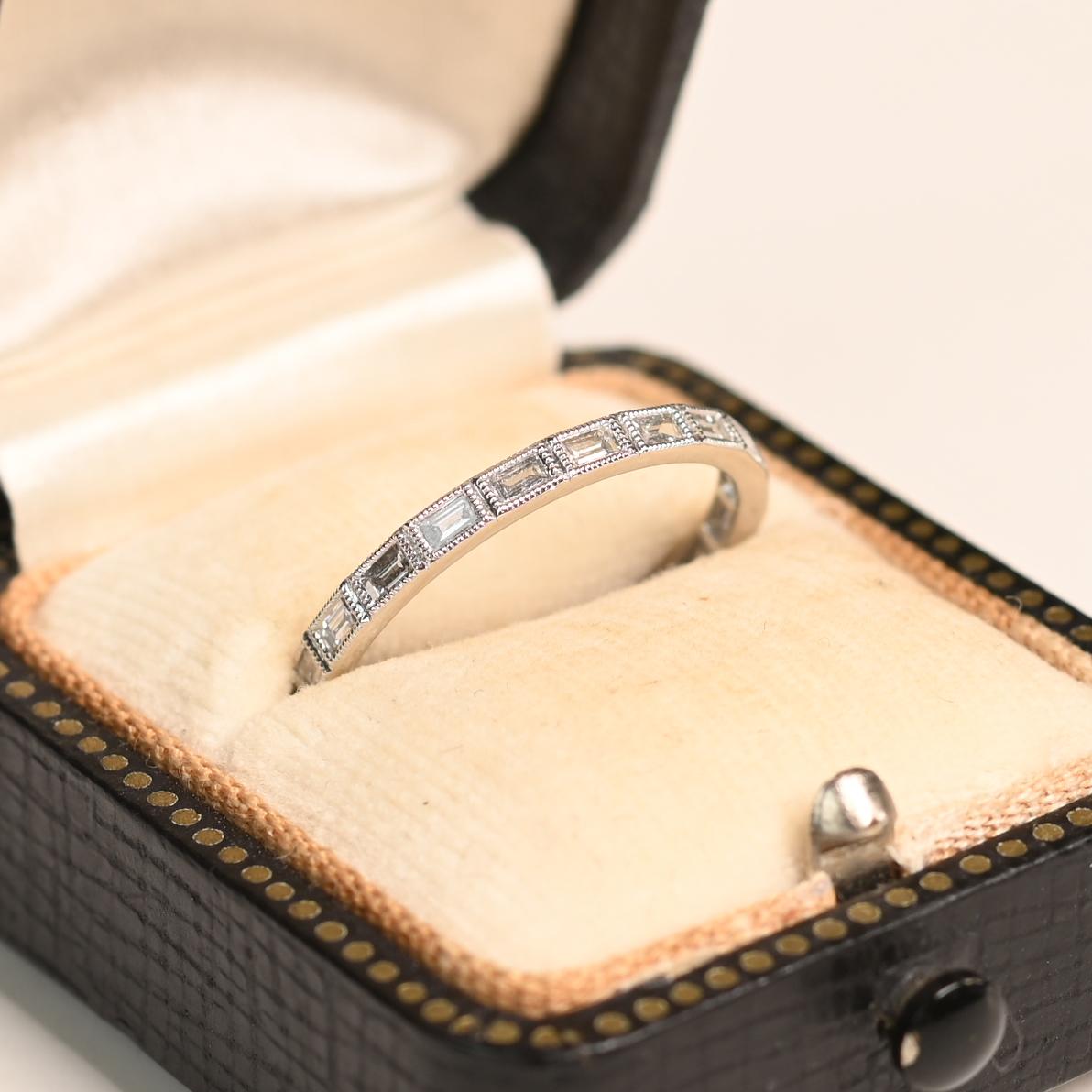 Questa raffinata fede nuziale in platino sfoggia un design eternità senza tempo, con diamanti taglio baguette incastonati senza soluzione di continuità intorno alla fascia. Con un peso totale di diamanti di circa 0,50 carati, ogni pietra è stata