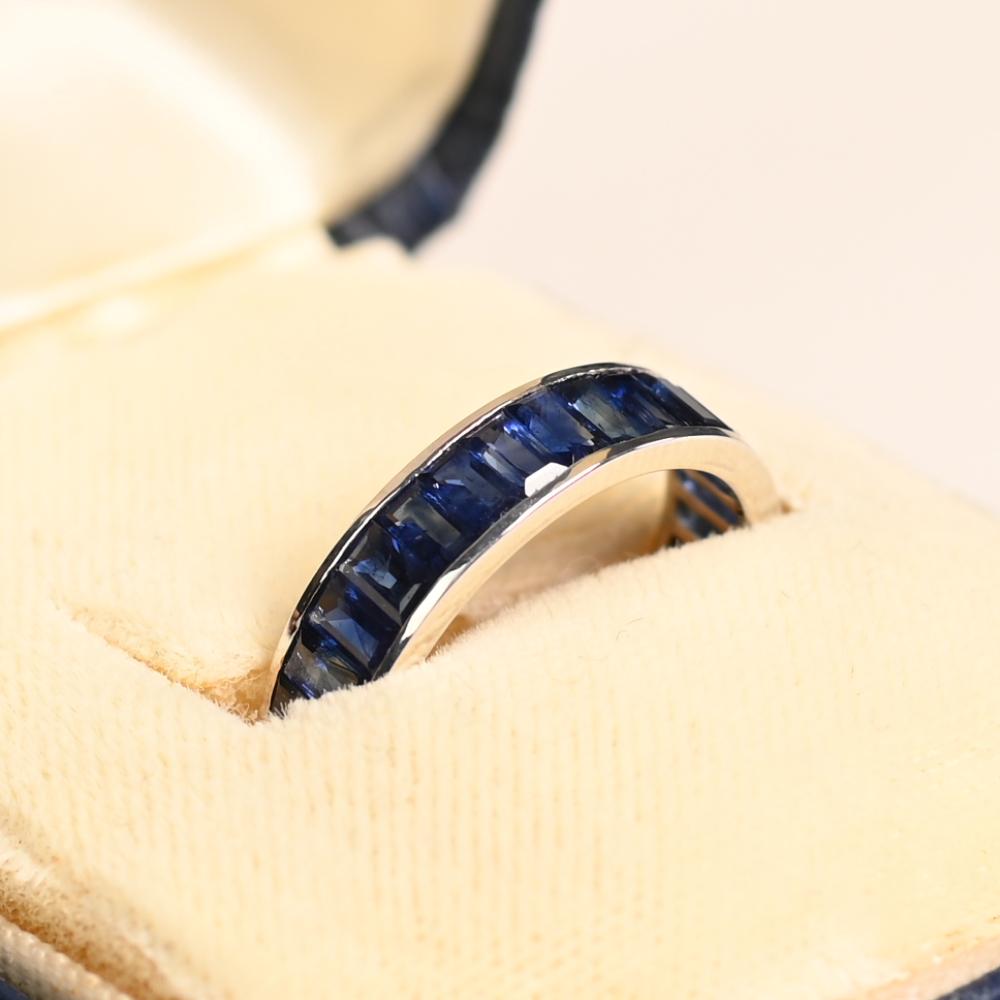 Cet exquis bracelet éternel en platine de 4,60 mm présente une rangée ininterrompue de saphirs taille baguette, élégamment sertis en canal dans une remarquable orientation nord-sud. Les teintes bleues riches et profondes des saphirs créent un