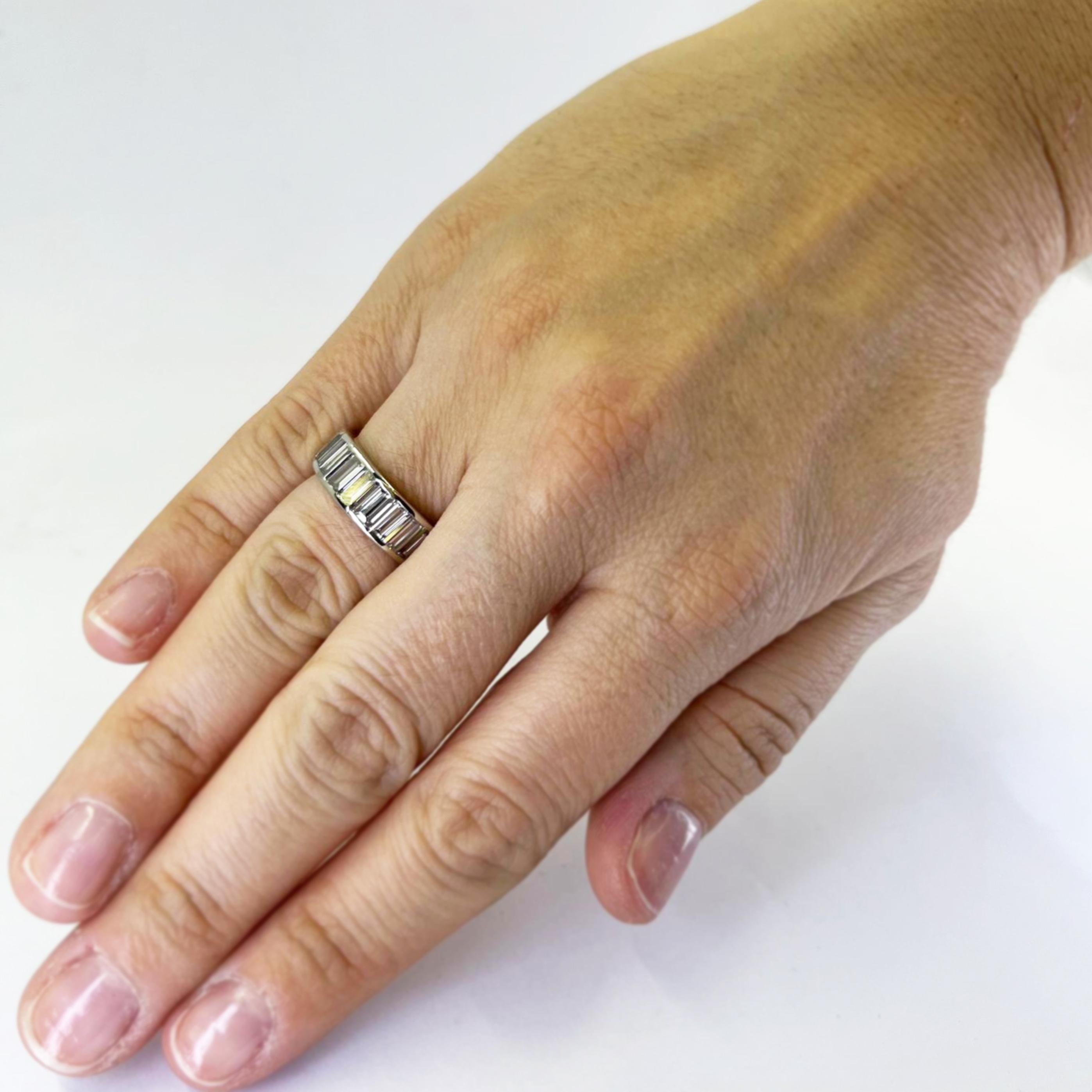Platinum and palladium 6.5mm wide channel set eternity band featuring 25 baguette cut diamonds of VS clarity and G color totaling approximately 5.00 carats. Finger size 6. Finished weight is 5.2 grams.