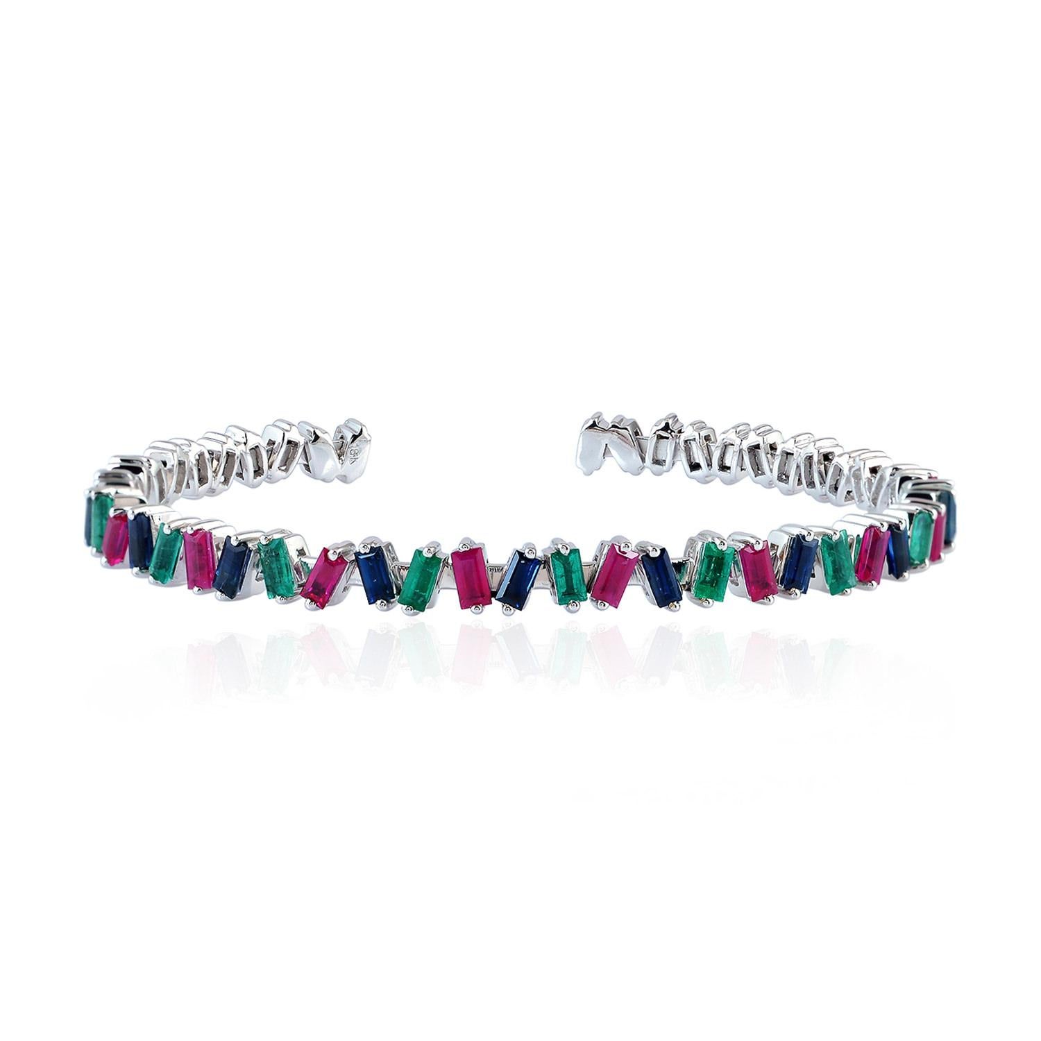 A beautiful bracelet handmade in 18K gold. It is set in 1.19 carats of baguette emeralds, 1.63 carats baguette rubies and baguette blue sapphire. Wear it alone or stack it with your favorite pieces. Bangle circumference is 6-in. Bangle is 3/16-in.