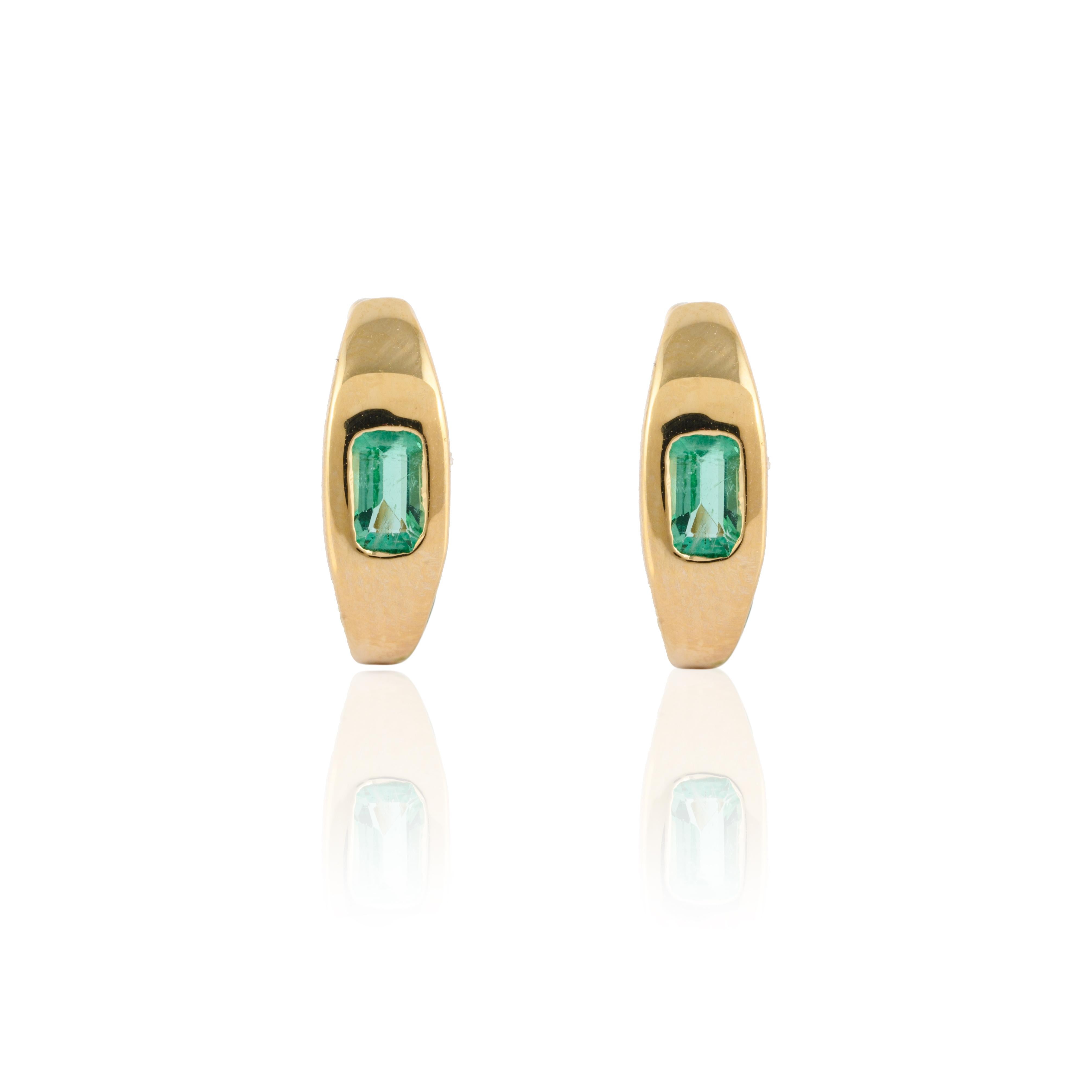 Minimalistische, mit Smaragden besetzte Huggie-Ohrringe aus 14-karätigem Gold, mit denen Sie ein Statement für Ihren Look setzen. Sie brauchen kleine Huggie-Ohrringe für das Büro, um mit Ihrem Look ein Statement zu setzen. Diese Ohrringe mit einem