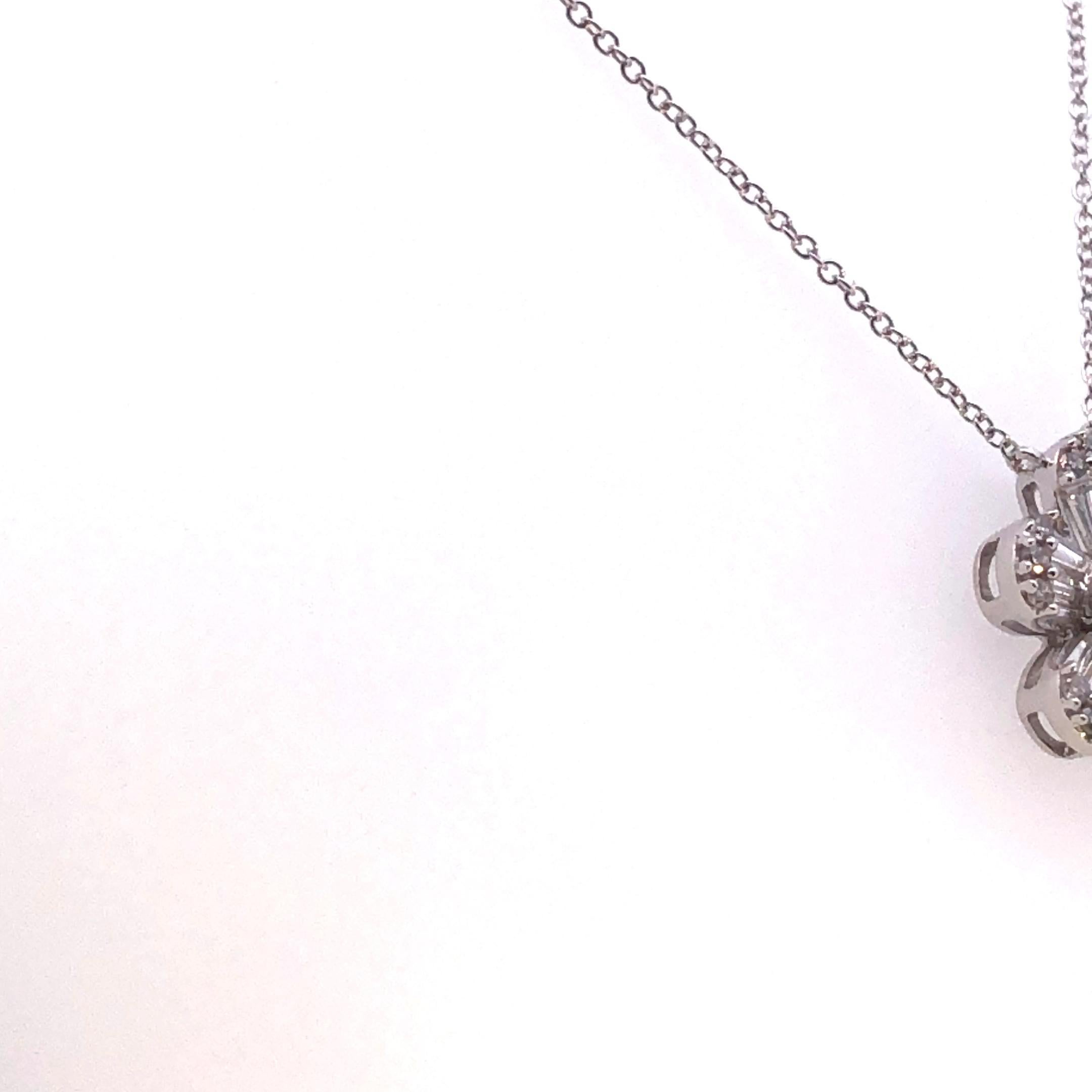 Simbolo di eleganza e grazia, questo ciondolo a fiore con diamanti tondi e baguette è una dichiarazione mozzafiato di bellezza senza tempo. Realizzato in oro bianco 14 carati, questo pendente presenta un motivo floreale meticolosamente disegnato,