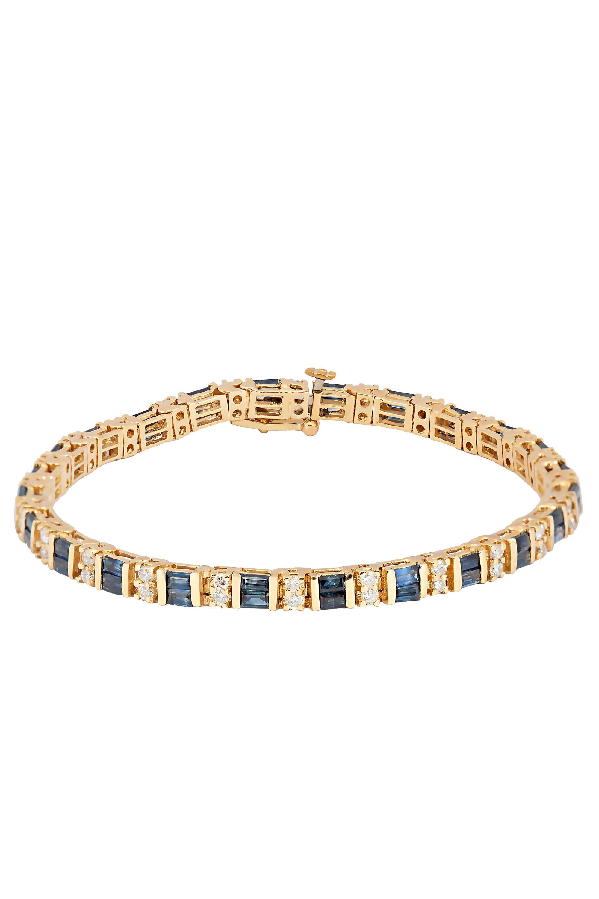 A classic tailored tennis bracelet crafted in 18 karat yellow gold and composed of rows of double stacked sapphire baguettes interspersed by stations of double stacked round brilliant diamonds. Set with a total of approximately 4.80 carats in