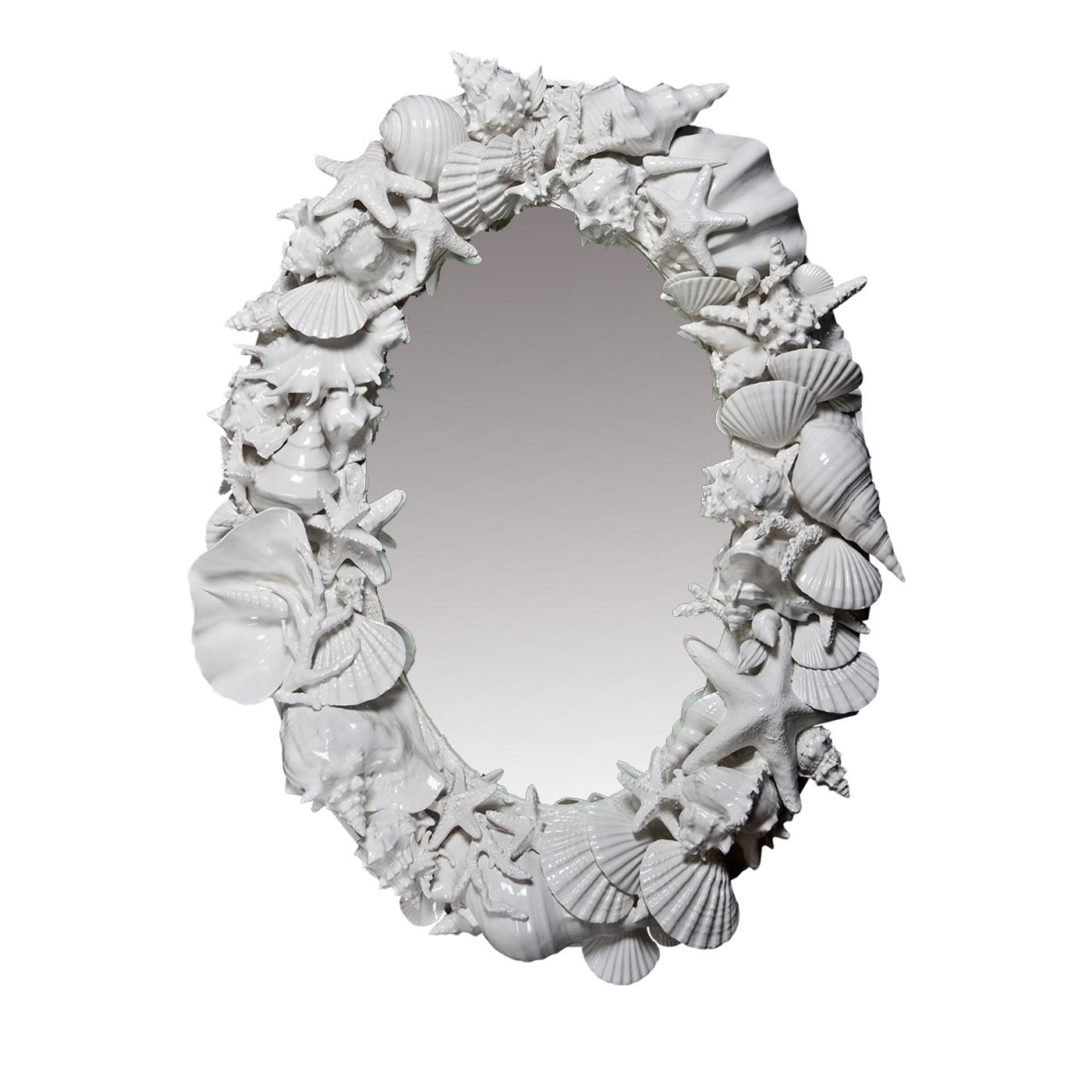 This is an oval mirror originally designed for a customer in the Bahamas in 1999. Mounted on a wooden frame, the mirror is encased by 90 hand-sculpted ceramic sea shells, lending the piece a radiant gleam of pure whiteness.