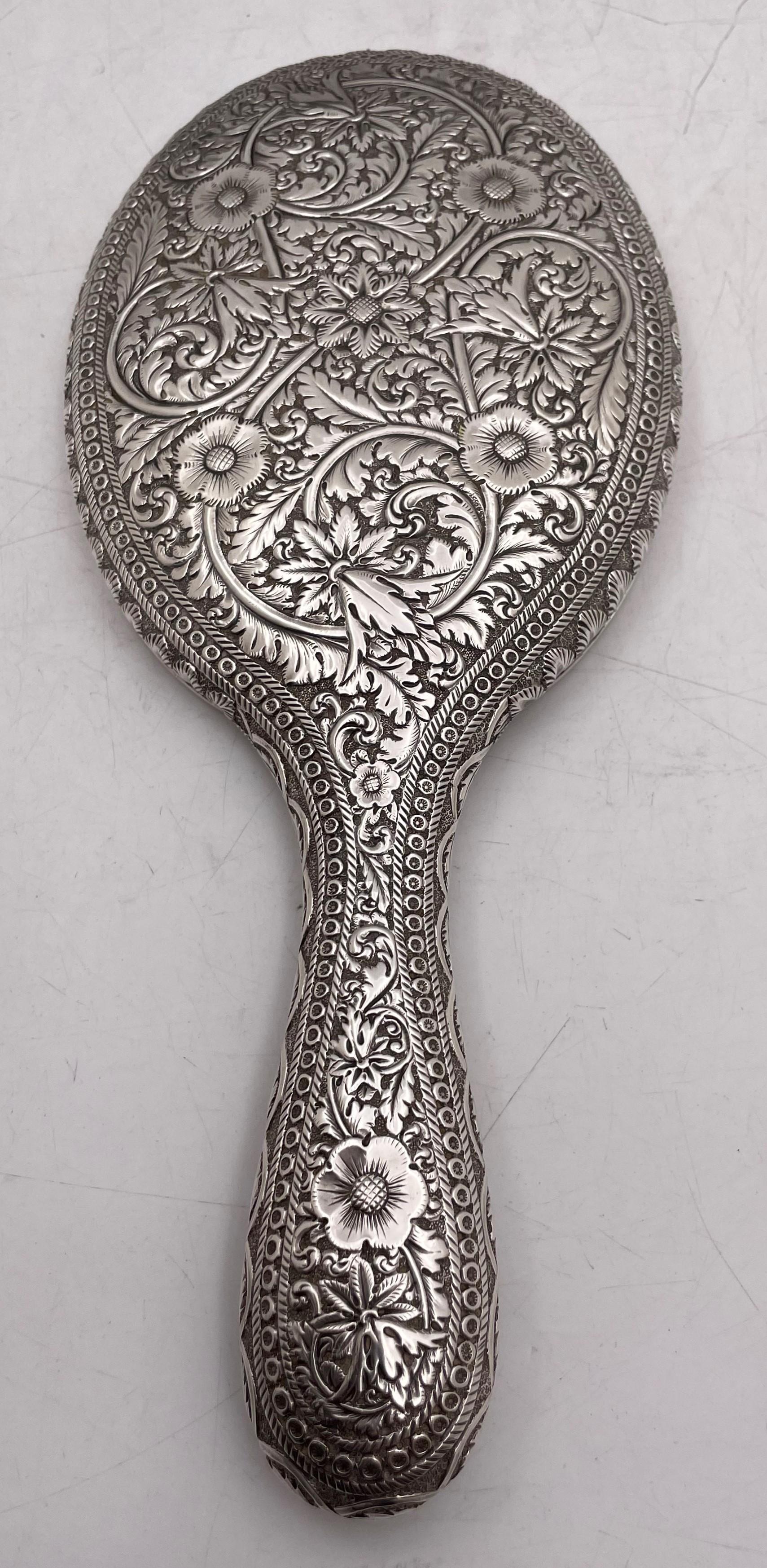 Bailey, Banks, and Biddle sterling silver and glass hand mirror from the 19th century, beautifully adorned with floral and curvilinear, geometric motifs, measuring 10 5/8'' in length by 4 1/2'' in width by 7/8'' in depth, and bearing hallmarks and a
