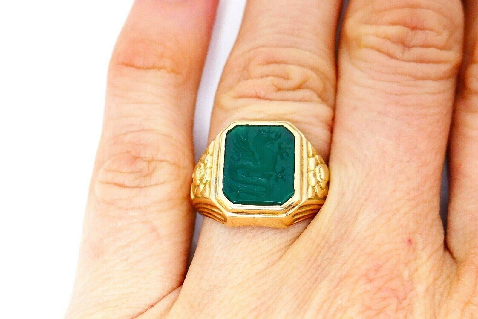 Bailey Banks and Biddle 14k yellow gold signet intaglio ring features chrysoprase with a carved dragon image. The ring has embossed elements on its sides and digits 