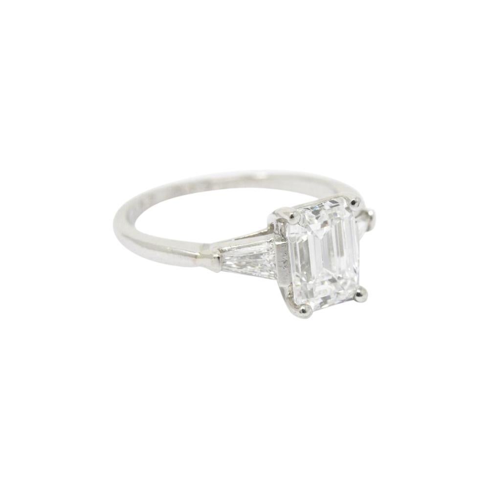 Centering a clean bright white emerald cut center diamond weighing 1.57 carats, E color and VVS2 clarity

Two tapered  baguette diamond accents weighing approximately 0.36 carat total weight

Top measures 8.36 mm and sits 5.80 mm high

The ring is