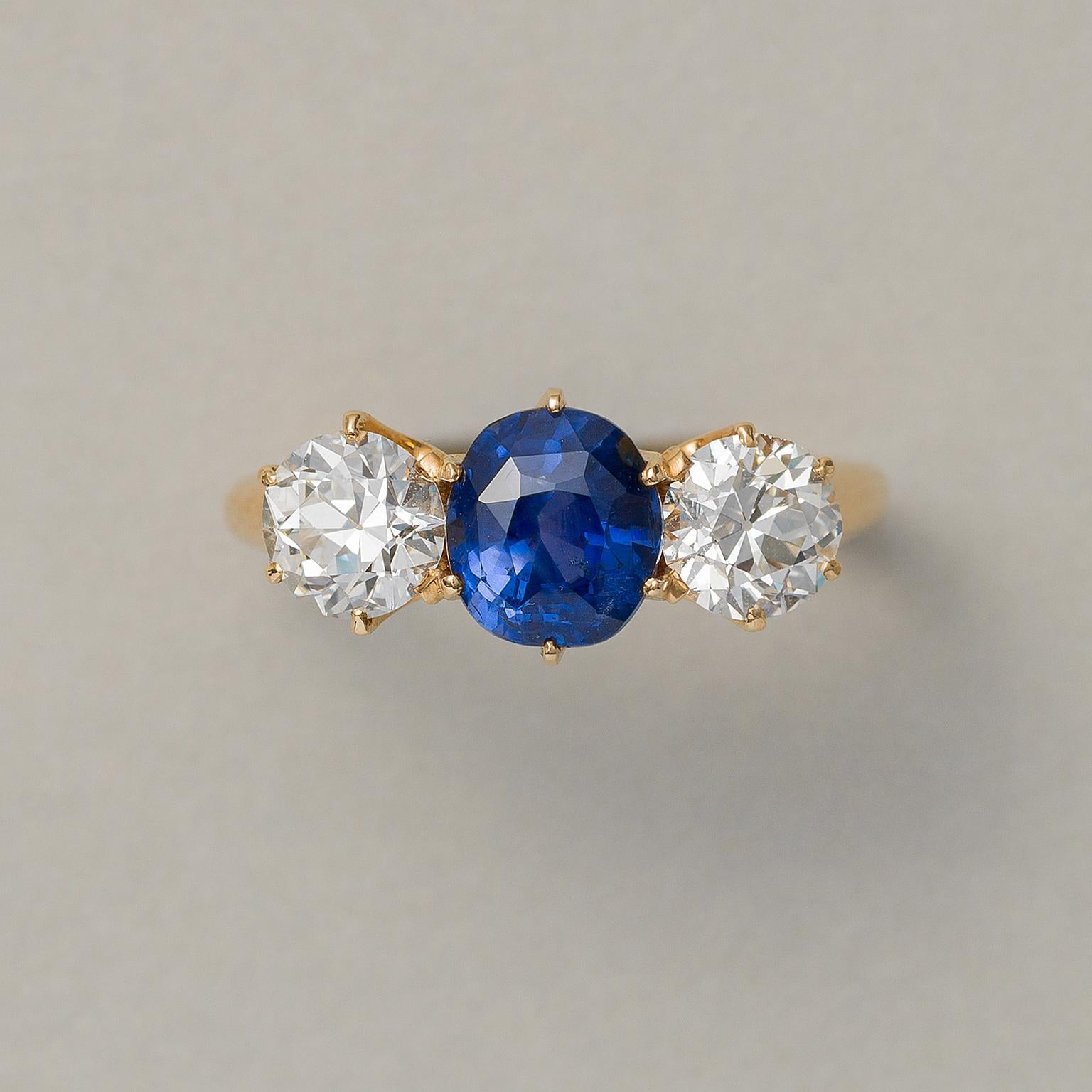 A beautiful 18 carat gold three-stone ring with two European cut diamonds (app. 0.80 carat in total F-G, VS) and in the middle one cushion cut natural non-heated Ceylon sapphire (2.63 carat, 7.6 x 6.7 x 5.6 mm), set in prongs settings, signed and