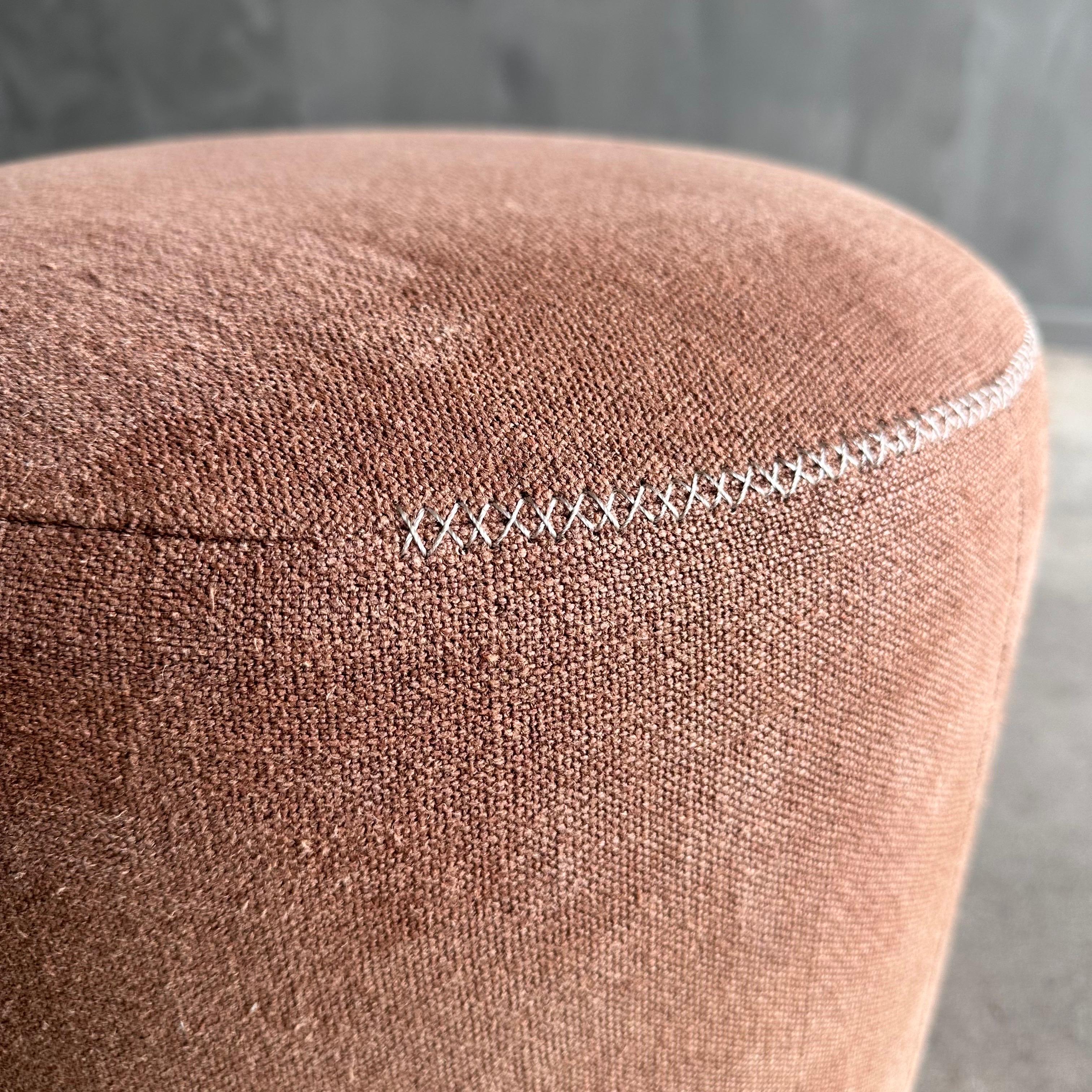 Ti presentiamo l'ottomana rotonda Bailey Petite, con eleganti gambe in quercia bianca rifinite in tono medio. Rivestito in un sofisticato lino pesante, questo pouf è versatile ed elegante. La robusta struttura in legno massiccio garantisce una lunga