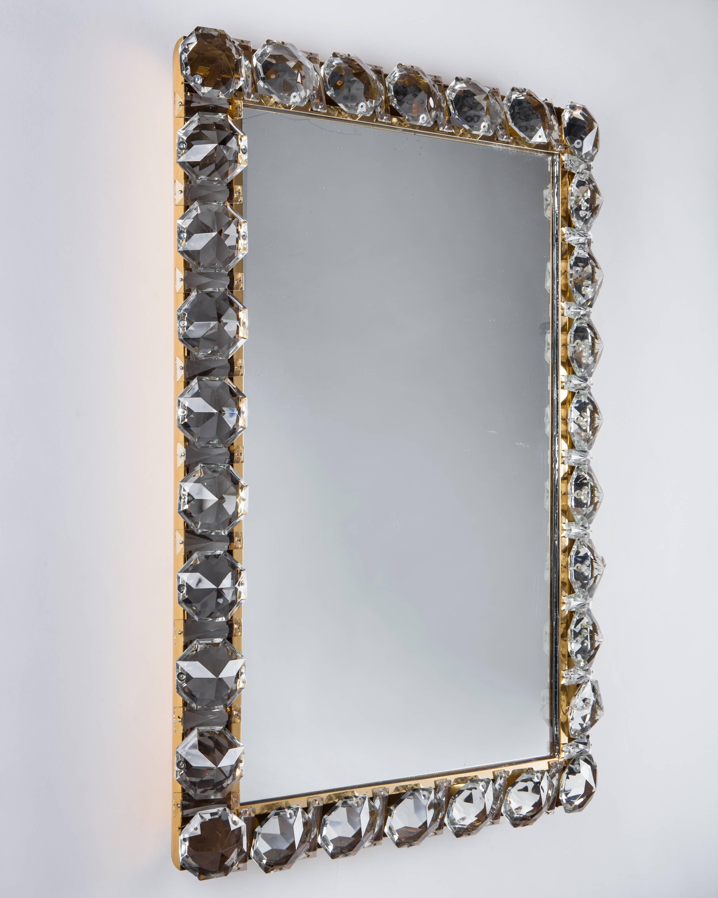 AMR1056
A vintage illuminated mirror set with faceted crystals on a gilded frame. Attributed to the Austrian maker Bakalowits & Sohne. Due to the antique nature of this fixture, there are some nicks or imperfections in the