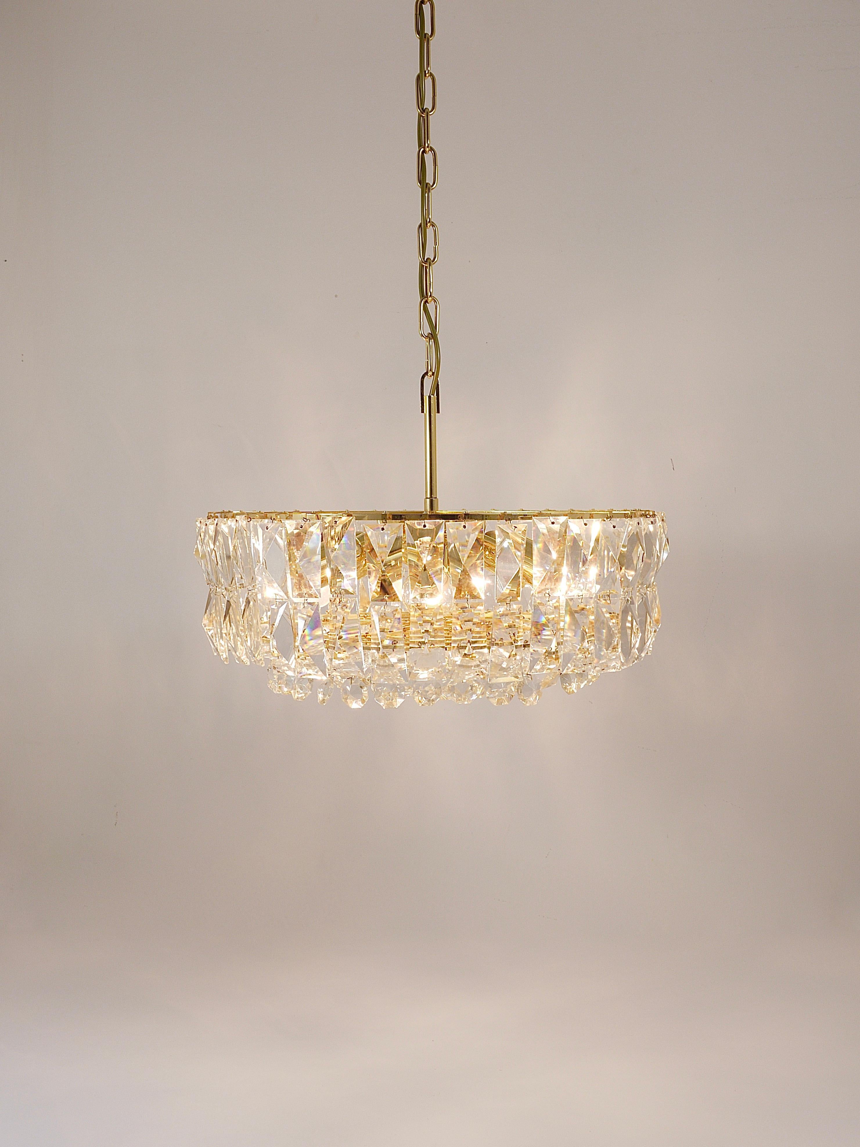 A stunning and large crystal chandelier handcrafted in the 1970s by Bakalowits & Söhne in Vienna, Austria. This exquisite piece features a gold-plated brass frame generously adorned with square and octagonal hand cut faceted crystals, creating a
