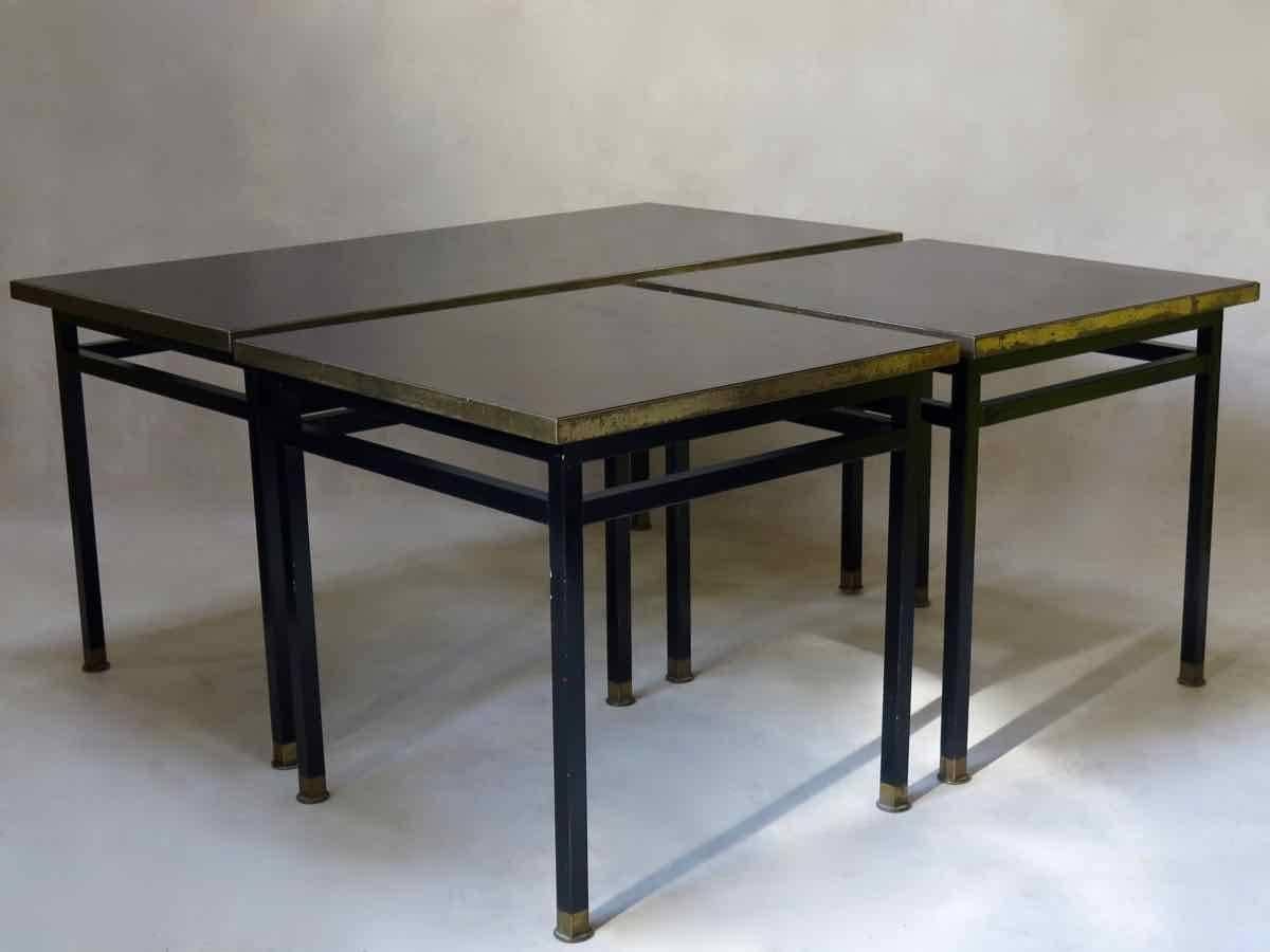 Chic set of three low tables with tubular iron bases, laquered in black paint and ending in brass sabots. The tabletops are black bakelite, with brass surrounds.

Heavy, very nice quality tables.

Dimensions provided below are for the larger,