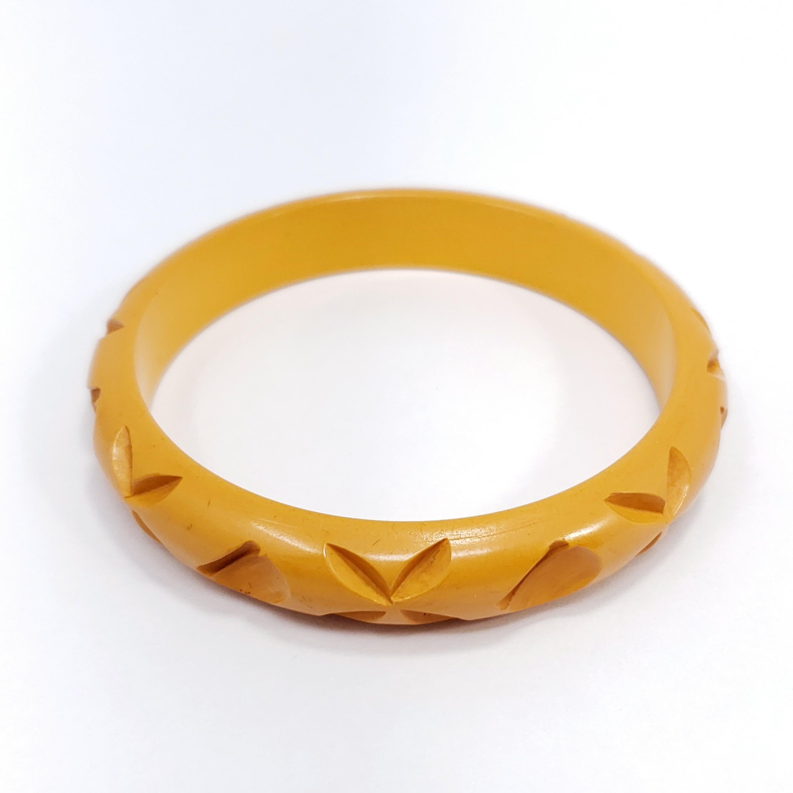 A vintage bakelite bangle bracelet with carved designs in golden butterscotch yellow color. 

Inner diameter: 6.45 cm
