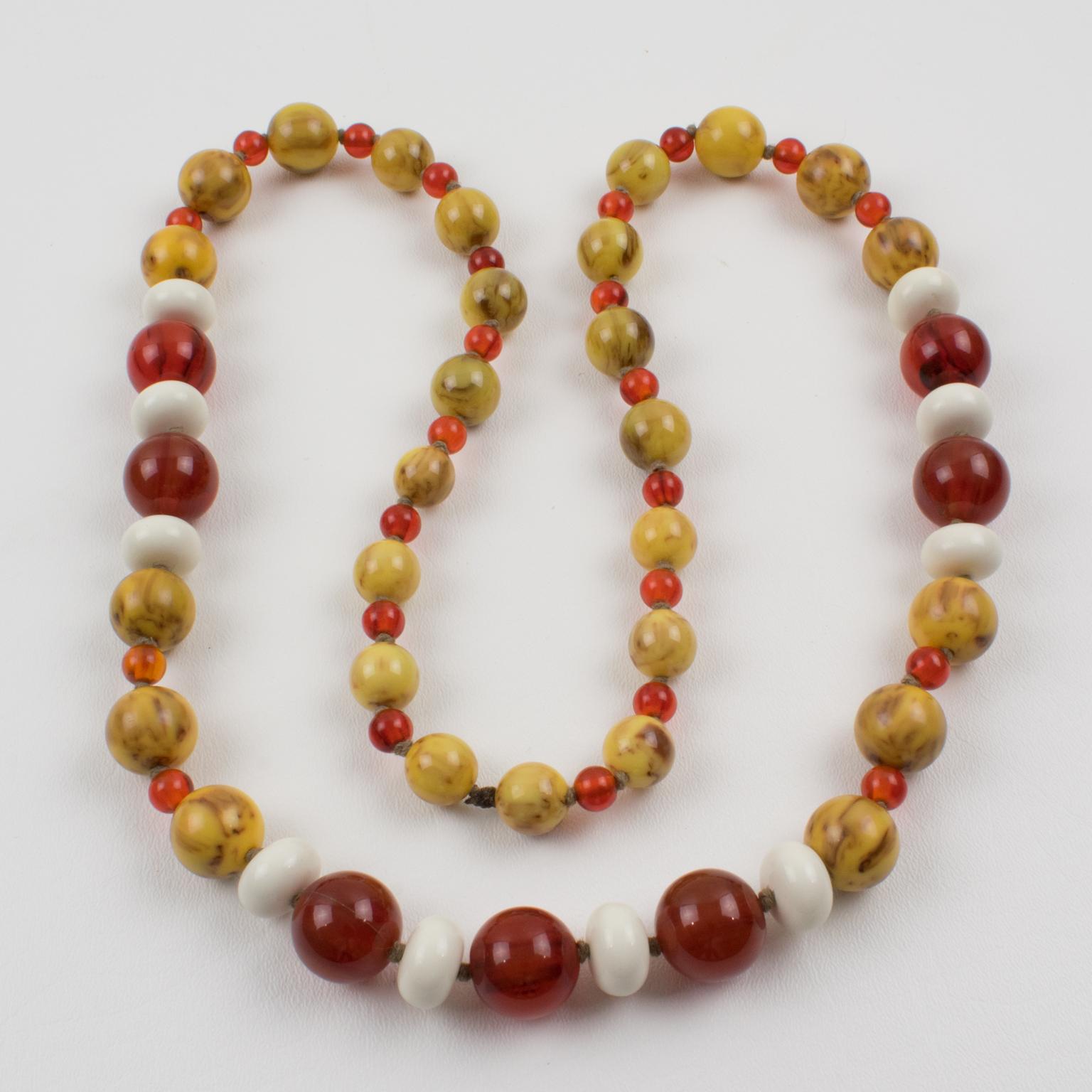 This superb extra-long beaded necklace features Bakelite and Lucite beads in assorted round and tomato shapes. The mix and match of fall colors boasts rootbeer marble, transparent red tea, and chocolate-custard marble contrasted with white Lucite