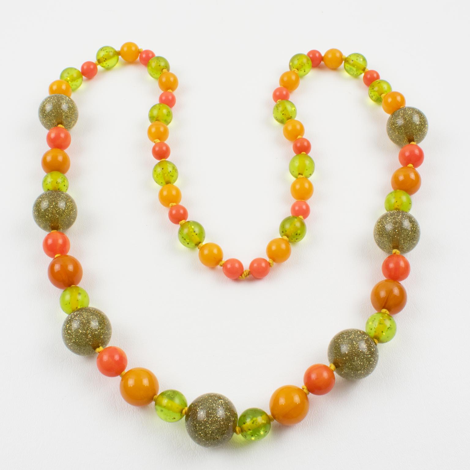 This superb extra-long Bakelite and Lucite beaded necklace was crafted in the 1980s with beads from the 1950s. The rounded beads have assorted sizes, and some have a pattern. Mix and match glittering colors boast burnt orange marble, tangerine