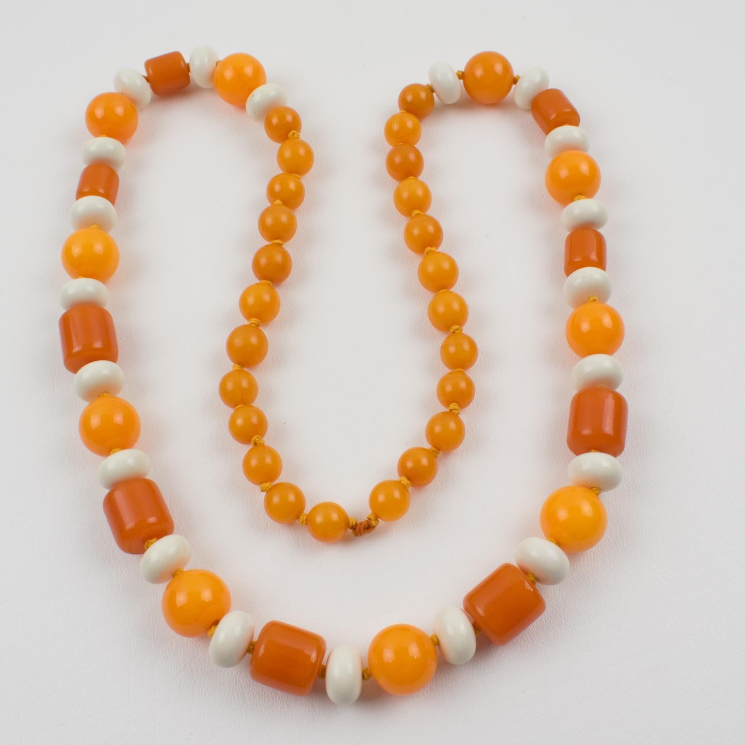 Ce ravissant collier extra-long en bakélite et lucite présente un assortiment de perles de différentes formes sculptées : rondes, tomates et bâtonnets. Le mélange de couleurs vives et ensoleillées se compose de marbre orange tangerine, de marbre