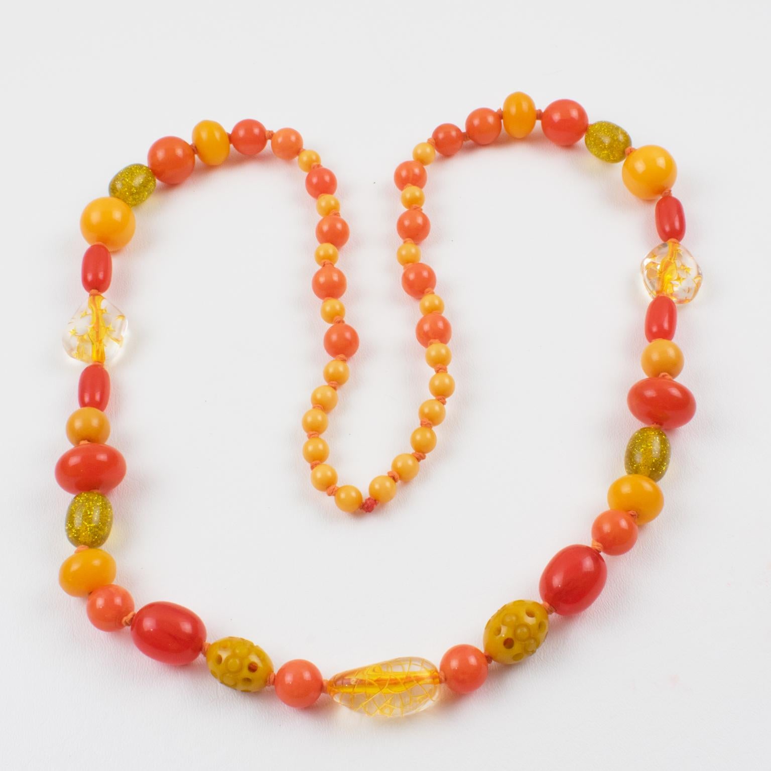 Ce collier extra-long coloré en bakélite et en lucite présente un assortiment de perles de différentes formes sculptées : rondes, tomates et ovales, certaines avec une sculpture et d'autres avec un motif. La pièce mélange les couleurs caramel, jaune