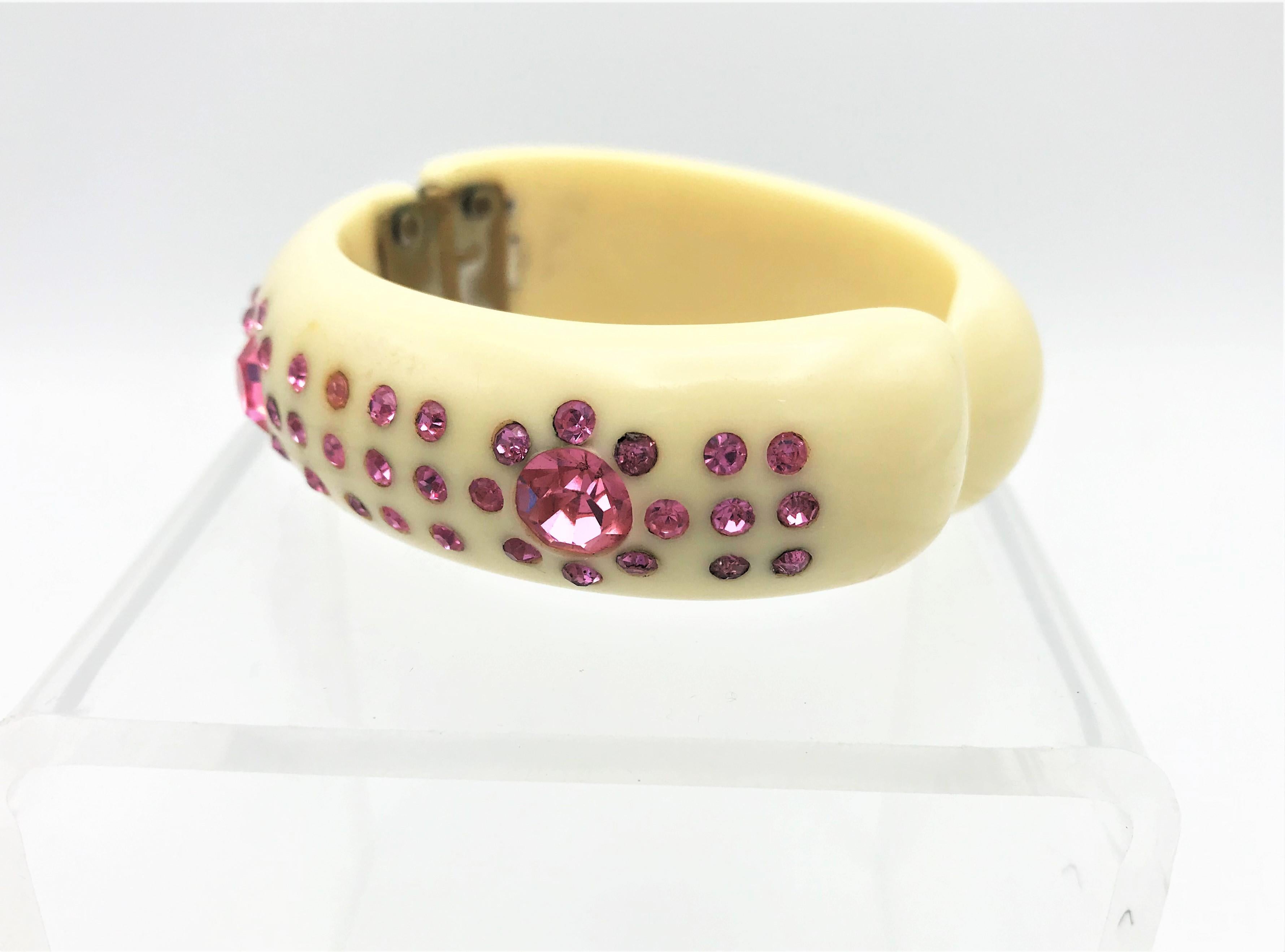 Very nice ivory colored bangle set with pink rhinestone and with hinge to open. 

Measurement: Width 2 cm inside, outside 3 cm, inner circumference 17 cm, the 2 pink strass stones are 1 cm diameter. Very good condition, no missing rhinestones. The