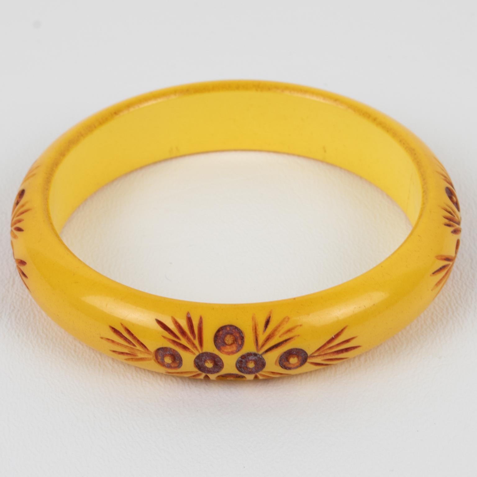 Ce charmant bracelet en bakélite présente une forme bombée massive avec une sculpture florale stylisée et contrastée autour d'elle. La couleur du bracelet est un jaune intense de maïs à la crème, contrastant avec la peinture rouge appliquée dans le
