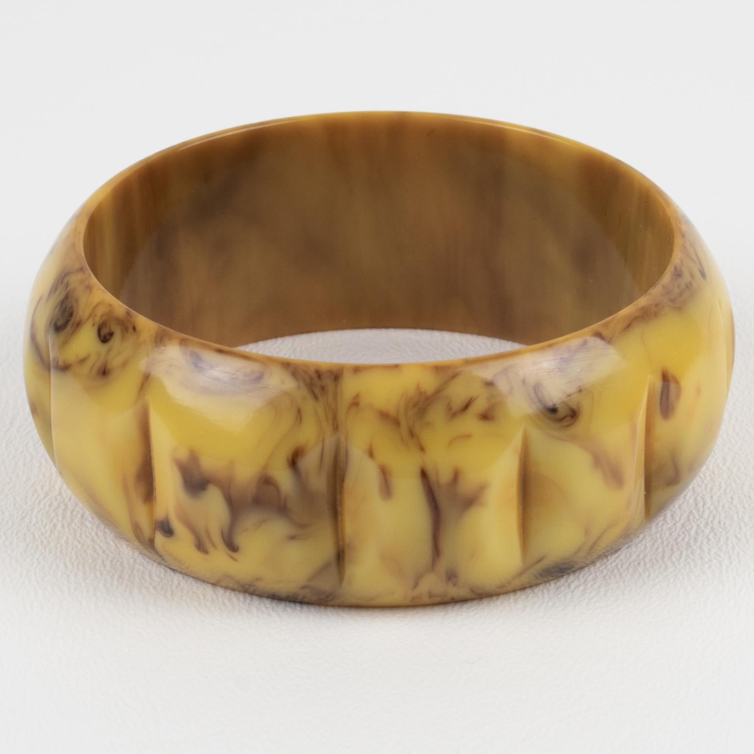 This is a lovely banana and chocolate marble Bakelite carved bracelet bangle. It features a chunky domed shape with deep geometric carving all around. The color is an intense light yellow banana marble tone with cloudy chocolate