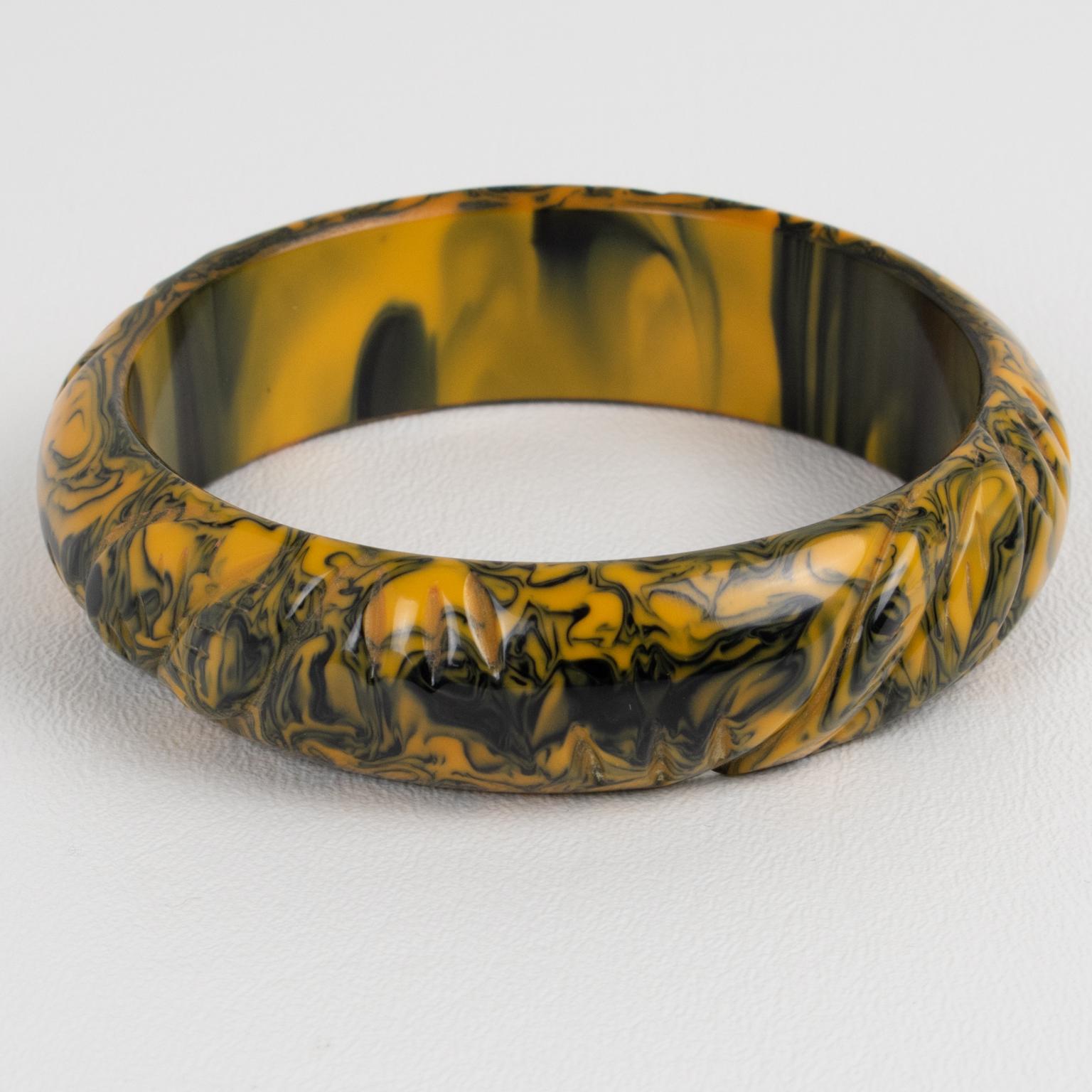 This is a lovely black and yellow butterscotch marble Bakelite carved bracelet bangle. The piece features a chunky domed shape with deep geometric carving all around. The color is an intense yellow butterscotch marble tone with black cloudy