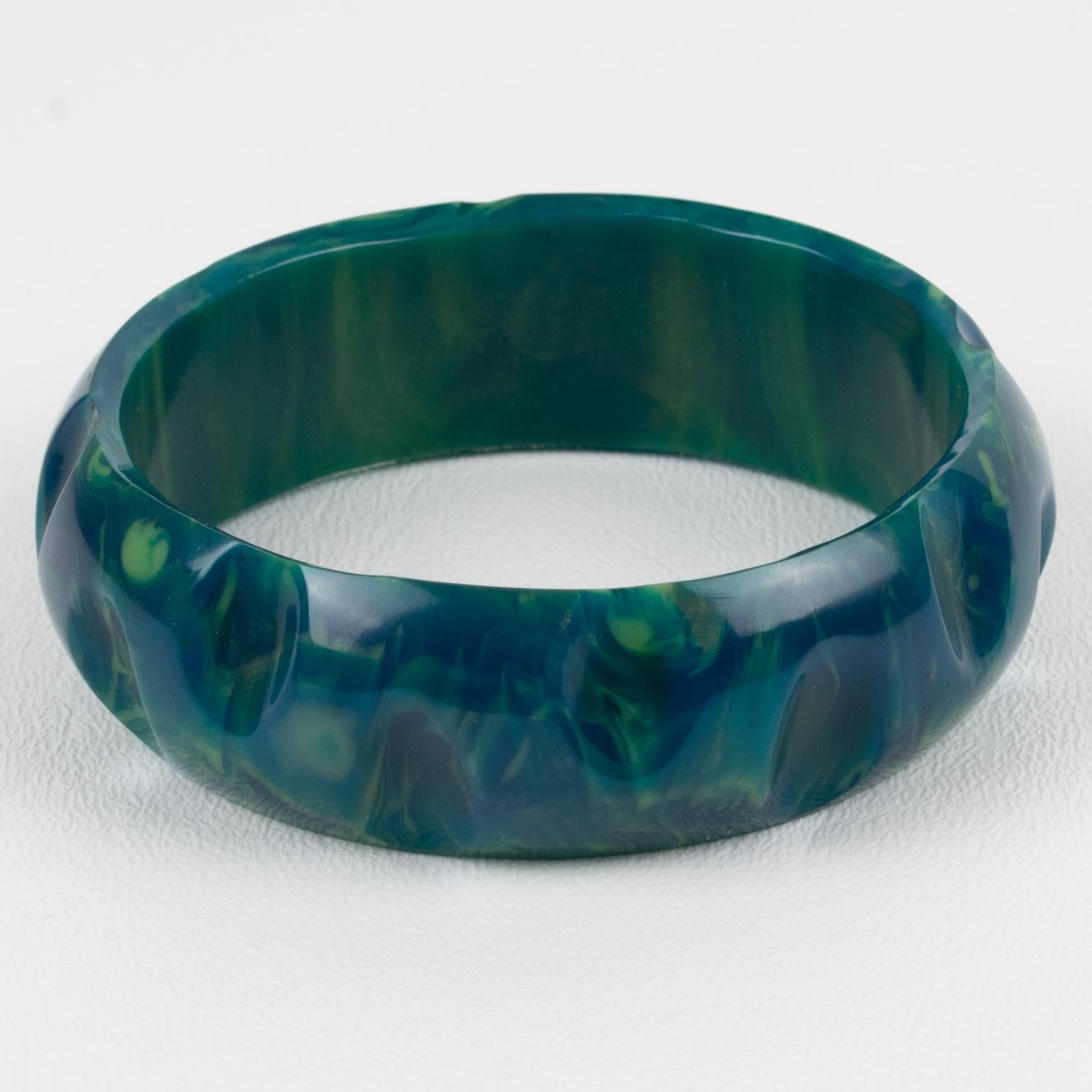 This is a gorgeous blue-moon marble Bakelite carved bracelet bangle. It features a chunky domed shape with a geometric carving design. The color is an intense blue marble with green and white cloudy swirling. 
Measurements: Inside across is 2.57 in