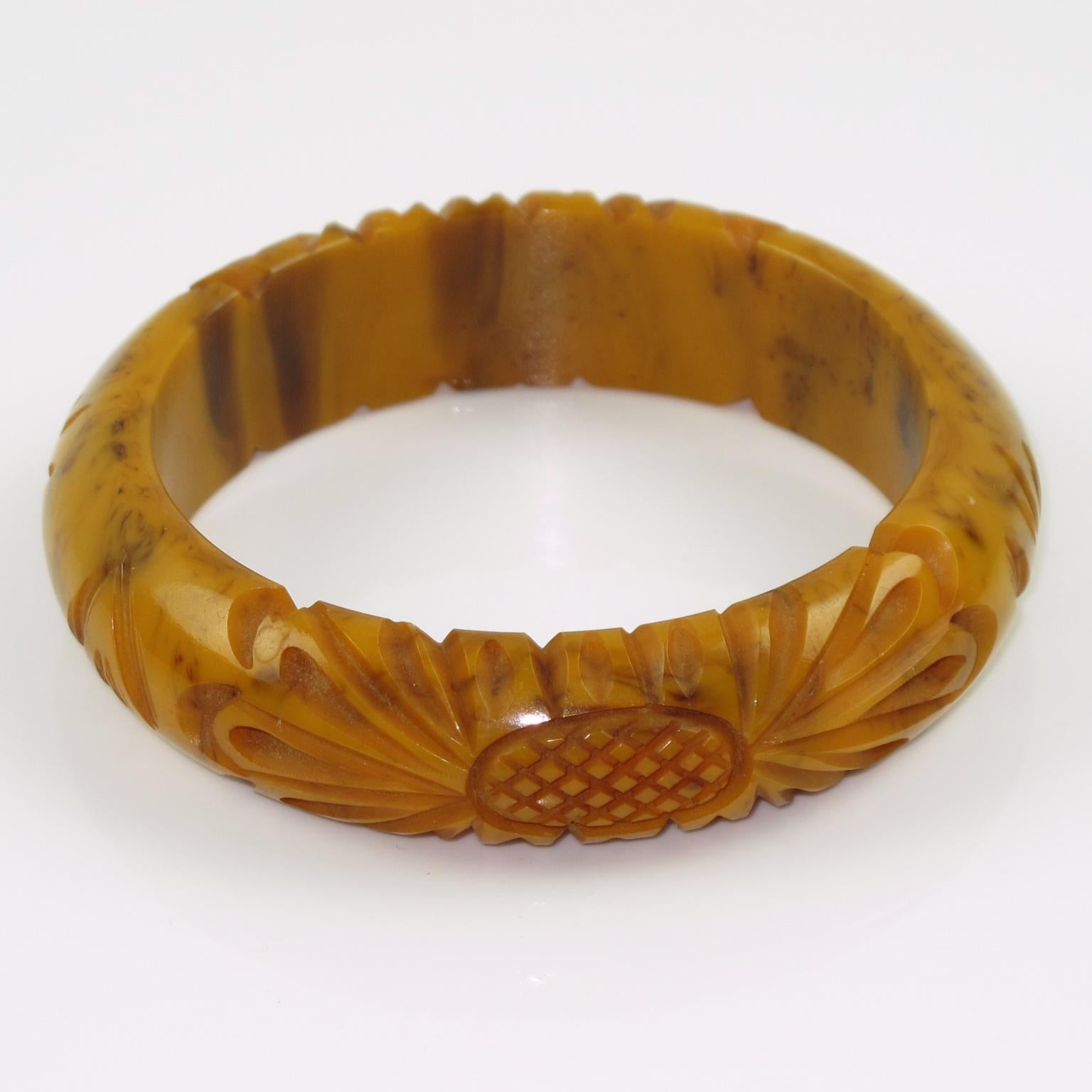 This stunning banana brown marble Bakelite carved bracelet bangle features a domed shape with deep floral carving, two designs on the bracelet, and a thick wall. The piece boasts an intense caramel yellow marbled tone with cloudy brown swirls, also