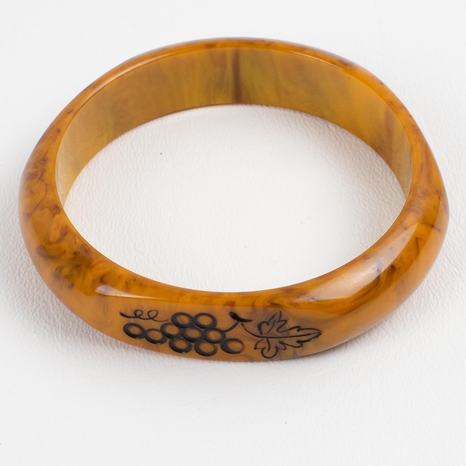 This stunning Mississippi swamp marble Bakelite carved bracelet bangle features a domed shape with three flat areas and carved designs. The design boasts bunches of grapes with black contrast. Intense gold butterscotch marble tone with black-brown