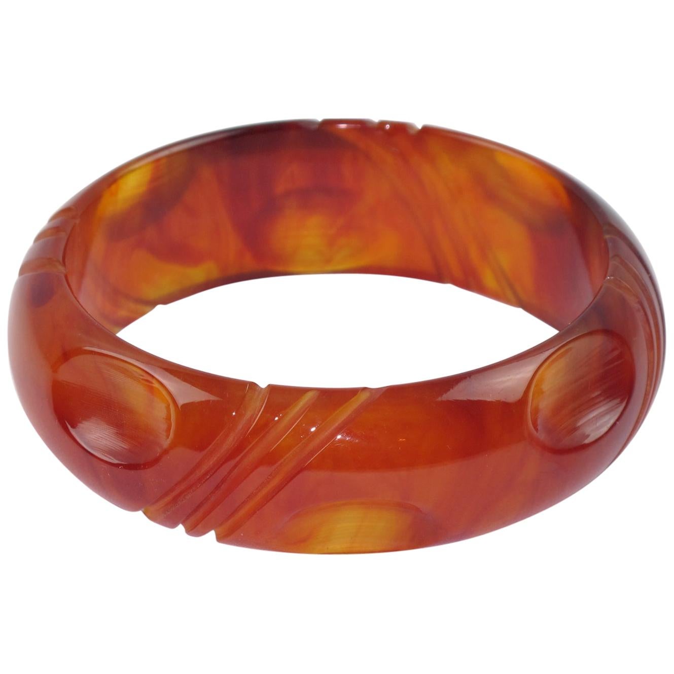 Elegant red tea amber marble Bakelite bracelet bangle. Chunky domed shape with a geometric deeply carved design all around. Red tea amber marble color with translucence and cloudy swirling. 
Measurements: Inside across is 2.63 in diameter (6.7 cm) -