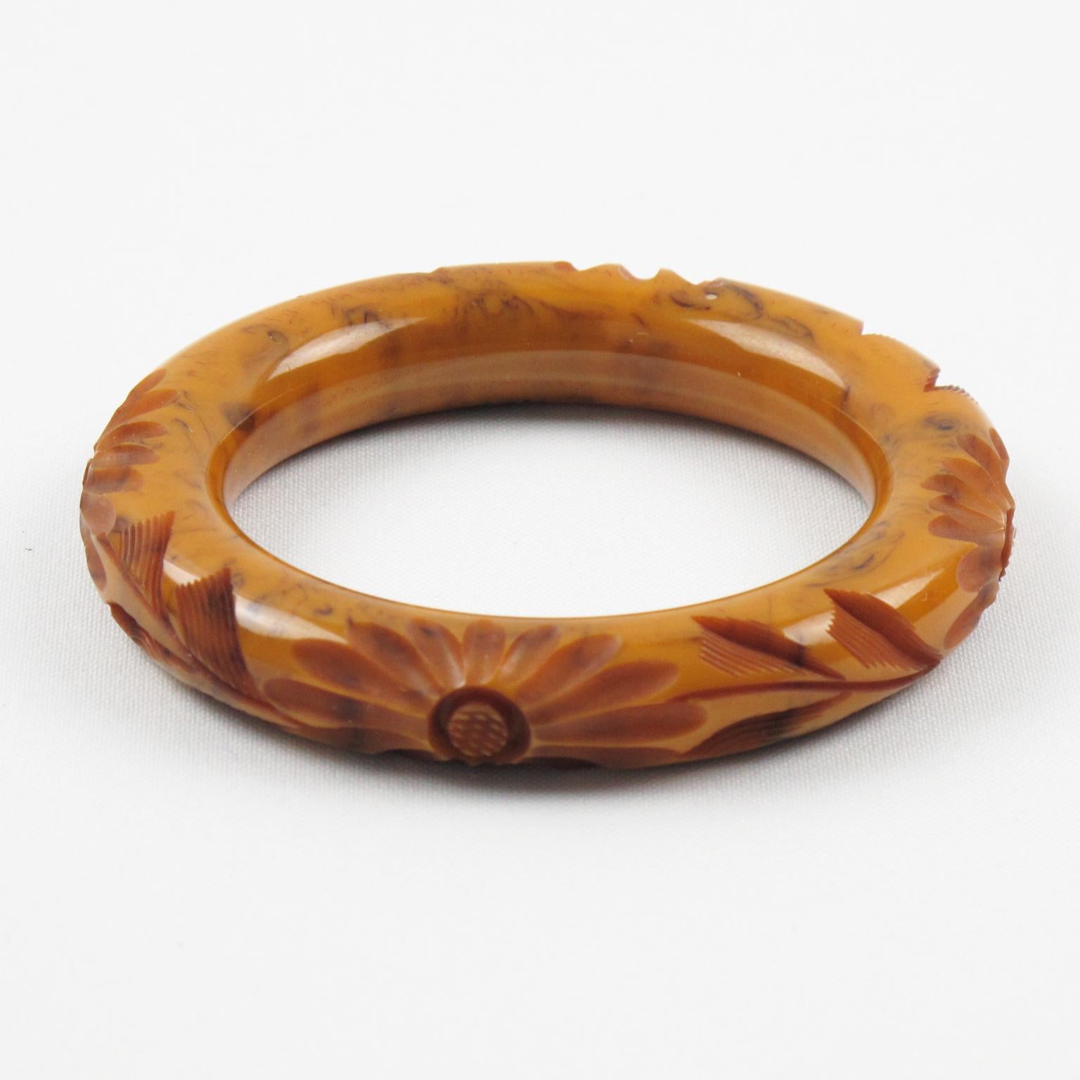 Questo splendido bracciale bangle in bachelite con sidro di mele e marmo nero ha una forma bombata e massiccia con profondi intagli floreali intorno. Il pezzo vanta un intenso colore di marmo sidro arancione dorato, con vortici neri e
