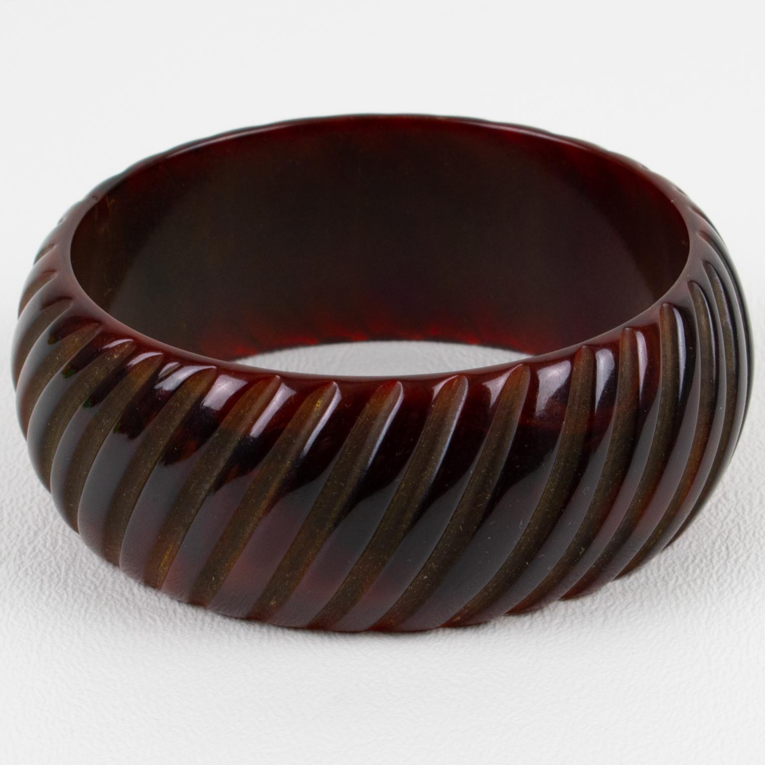 This is a fabulous red sangria Bakelite bracelet bangle. It features a chunky domed shape with geometric and deeply carved designs all around. The color is an intense dark red marble tone with a chocolate brown overtone. 
Measurements: Inside across