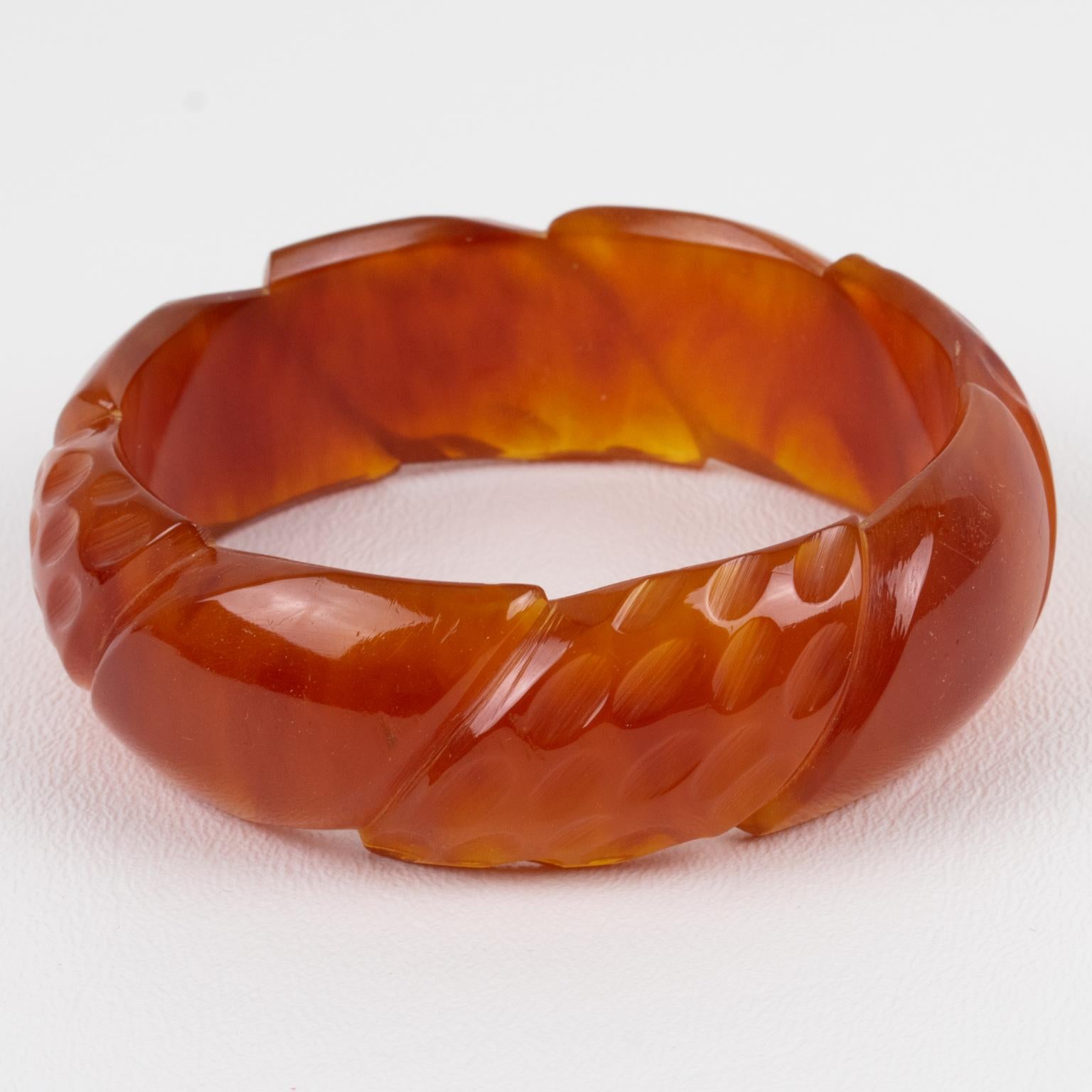 This is a gorgeous red tea amber marble Bakelite carved bracelet bangle. It features a chunky domed shape with deep geometric carving all around. The color is an intense amber marble tone with red tea cloudy swirling and some transparency.
The