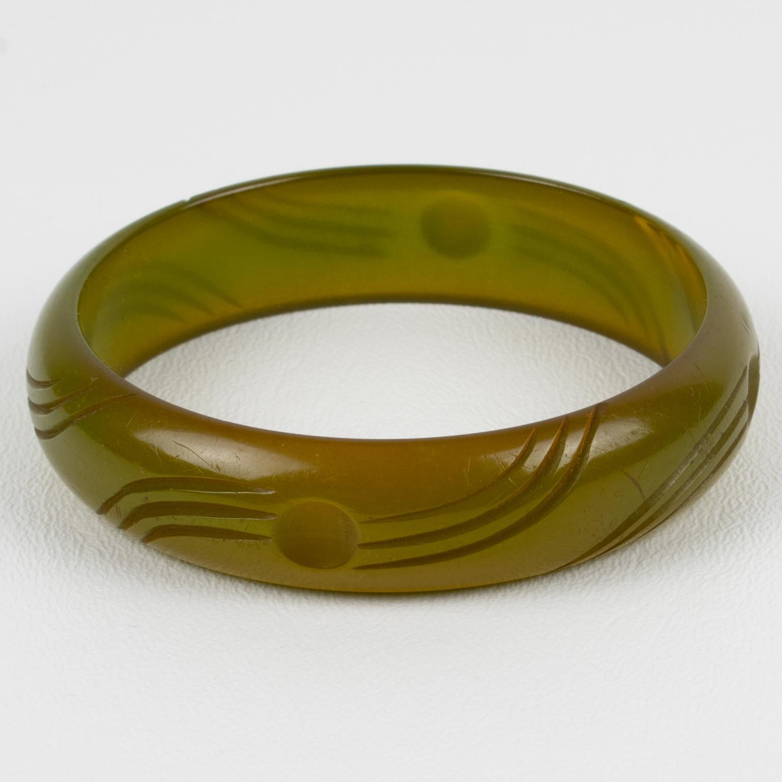This is a stunning asparagus green Bakelite carved bracelet bangle. It features a spacer domed shape with deep geometric carving all around. The color is an intense green tone with a yellow-orange overtone and light transparency. 
The bracelet is in