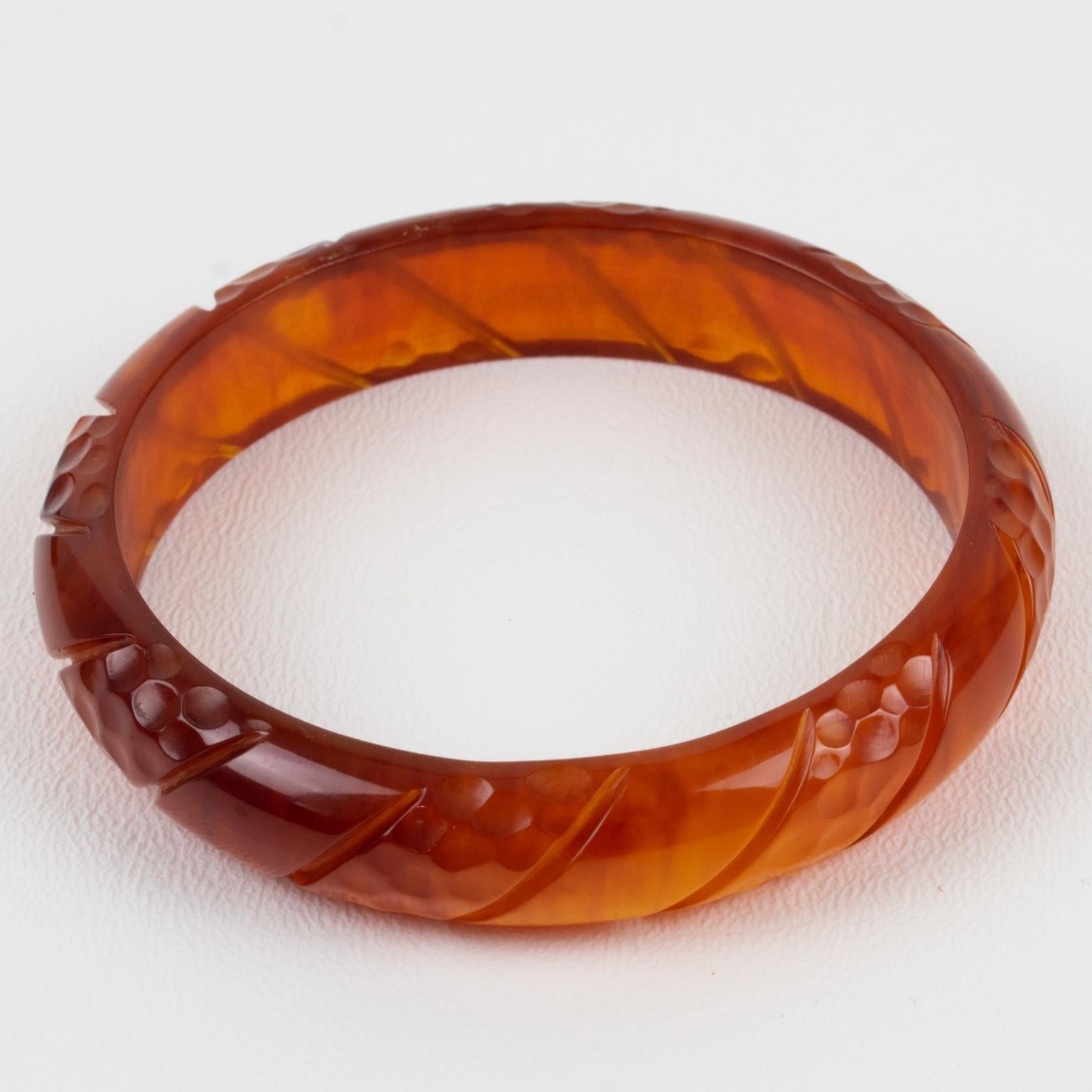 This is a lovely red tea amber Bakelite carved bracelet bangle. It features a spacer domed shape with deep geometric carving all around. The color is an intense red-amber tone with complete transparency. 
Measurements: Inside across is 2.63 in
