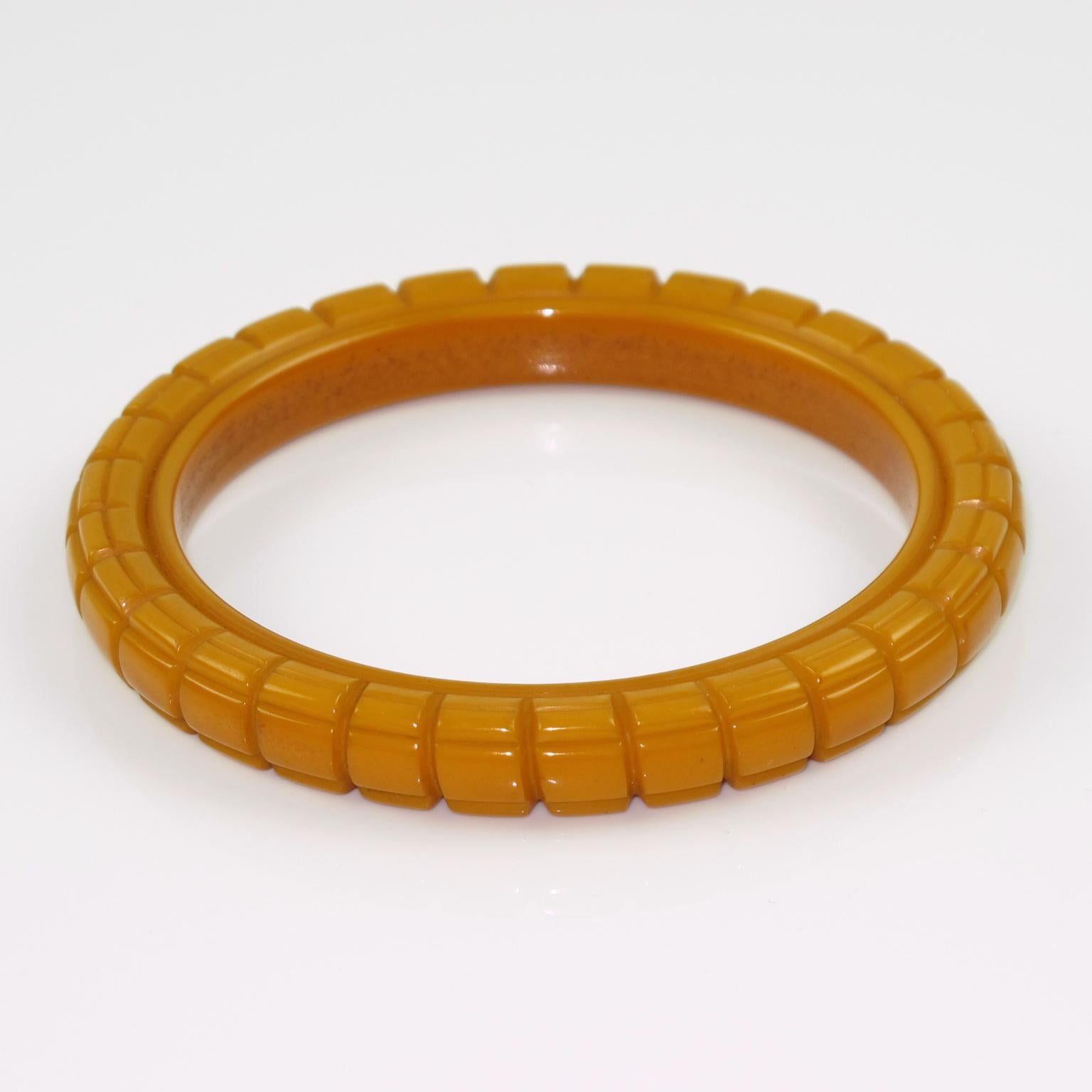 Este asombroso brazalete de baquelita tallada de color caramelo tiene forma de cúpula espaciadora con profundos tallados geométricos alrededor y una gruesa pared. La pieza presenta un intenso color amarillo caramelo. 
Medidas: El diámetro interior