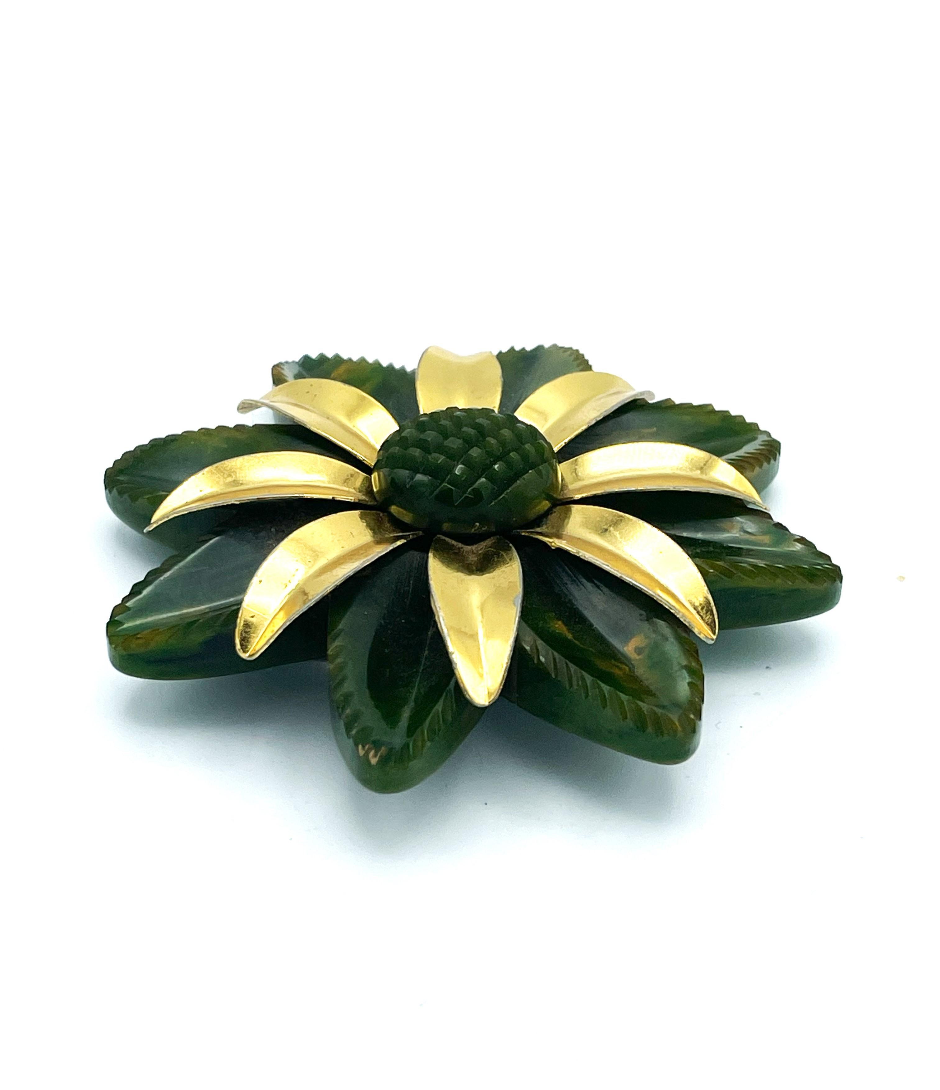 Très belle parure en bakélite verte composée d'un bracelet manchette avec une fleur en bakélite verte avec des pétales dorés et un pistil en bakélite. Il existe également une broche fleur en bakélite assortie, avec les mêmes feuilles dorées.
