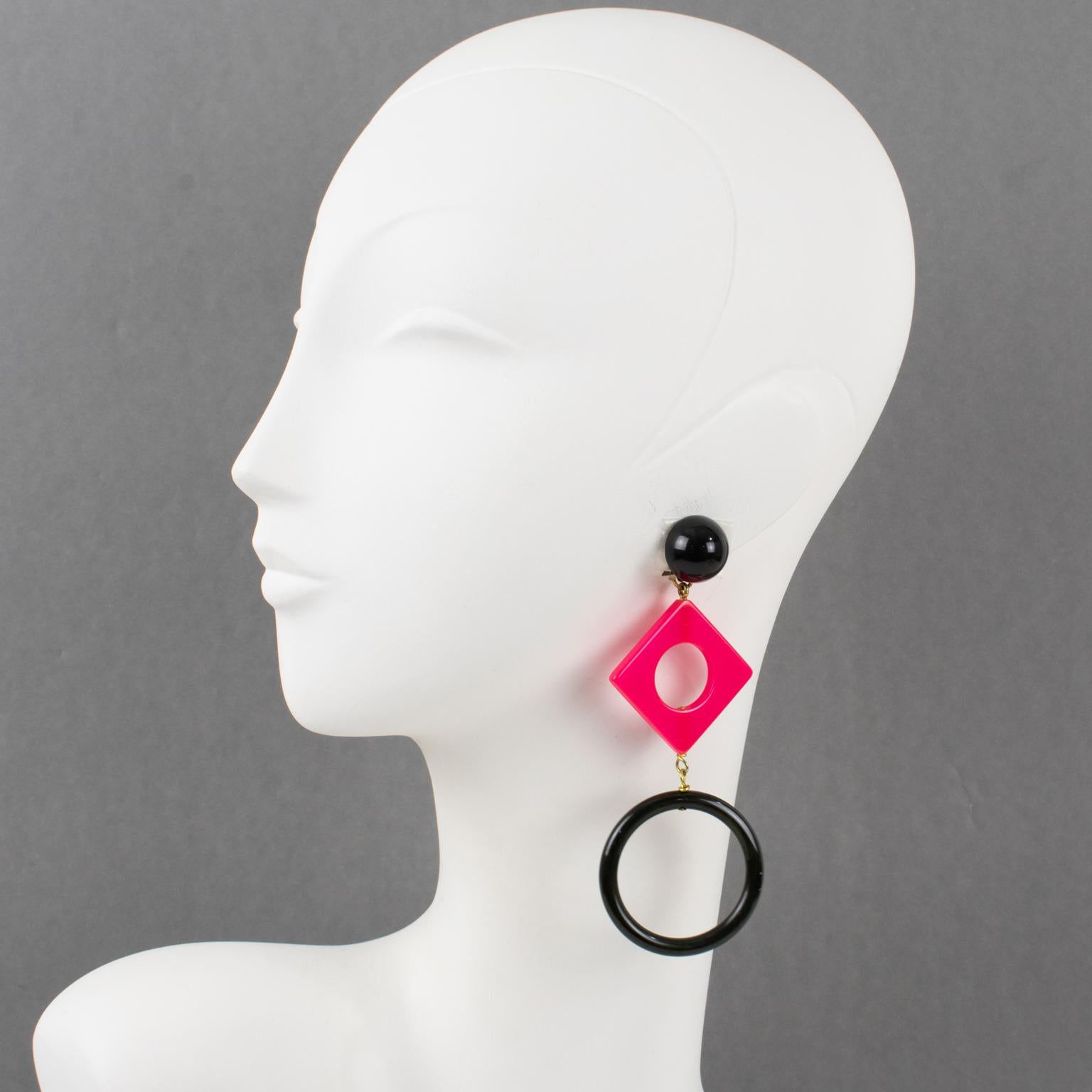 These lovely extra-long Bakelite dangling clip-on earrings with a Pop Art design style feature a shoulder-duster shape with a geometric design using square and circle forms. True licorice black is contrasted with a hot pink color. There is no