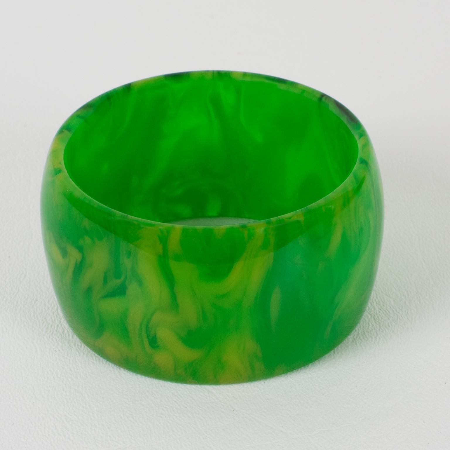 Questo splendido braccialetto oversize in marmo verde erba di bachelite presenta una forma a cupola larga e robusta. Il pezzo vanta un'intensa tonalità di marmo verde, con vortici e traslucidità gialla e bianca. 
Misure: Il diametro interno è di