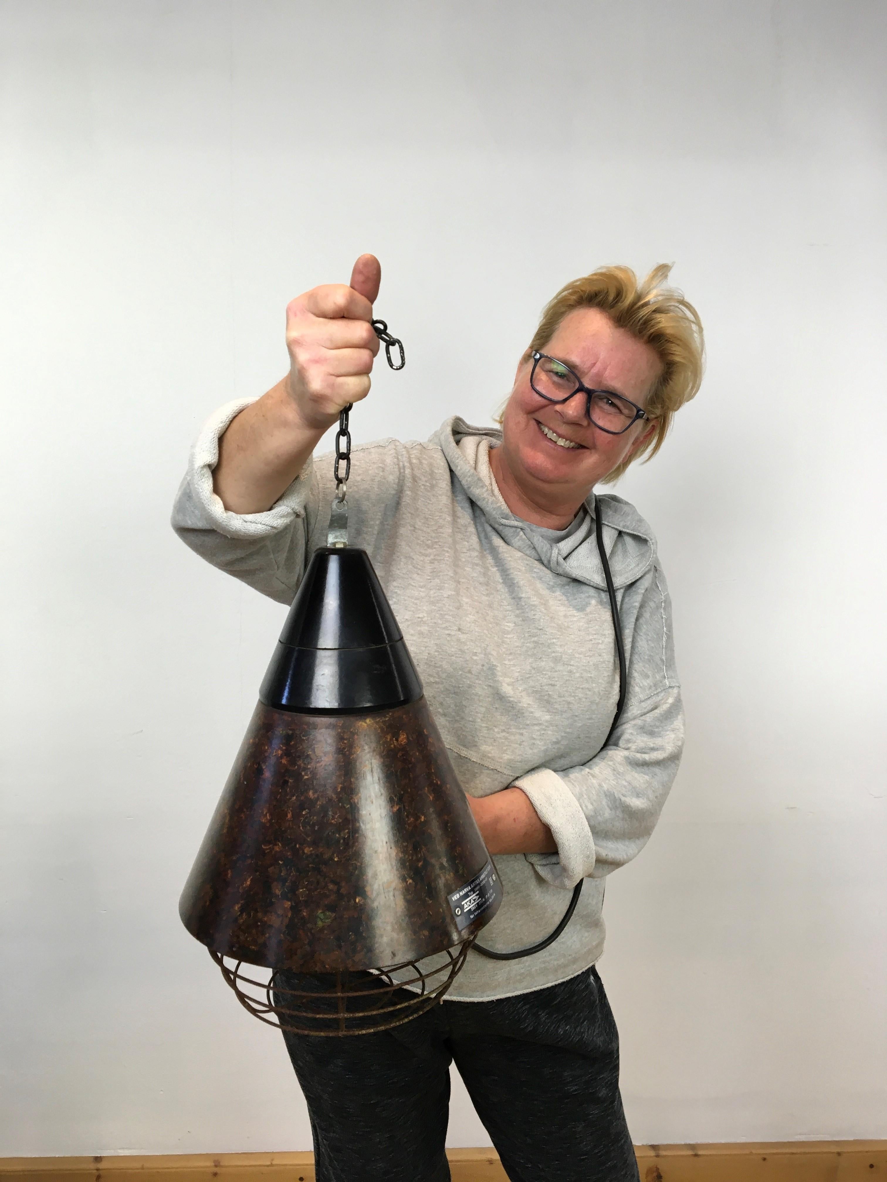 German bakelite industrial pendant light. 
Industrial lighting with a conic shape and a cage or grid under. 
Inside a porcelain E27 fitting. 
Beautiful brown flamed - speckled bakelite with the original brand plates still on the light. VEB NARVA