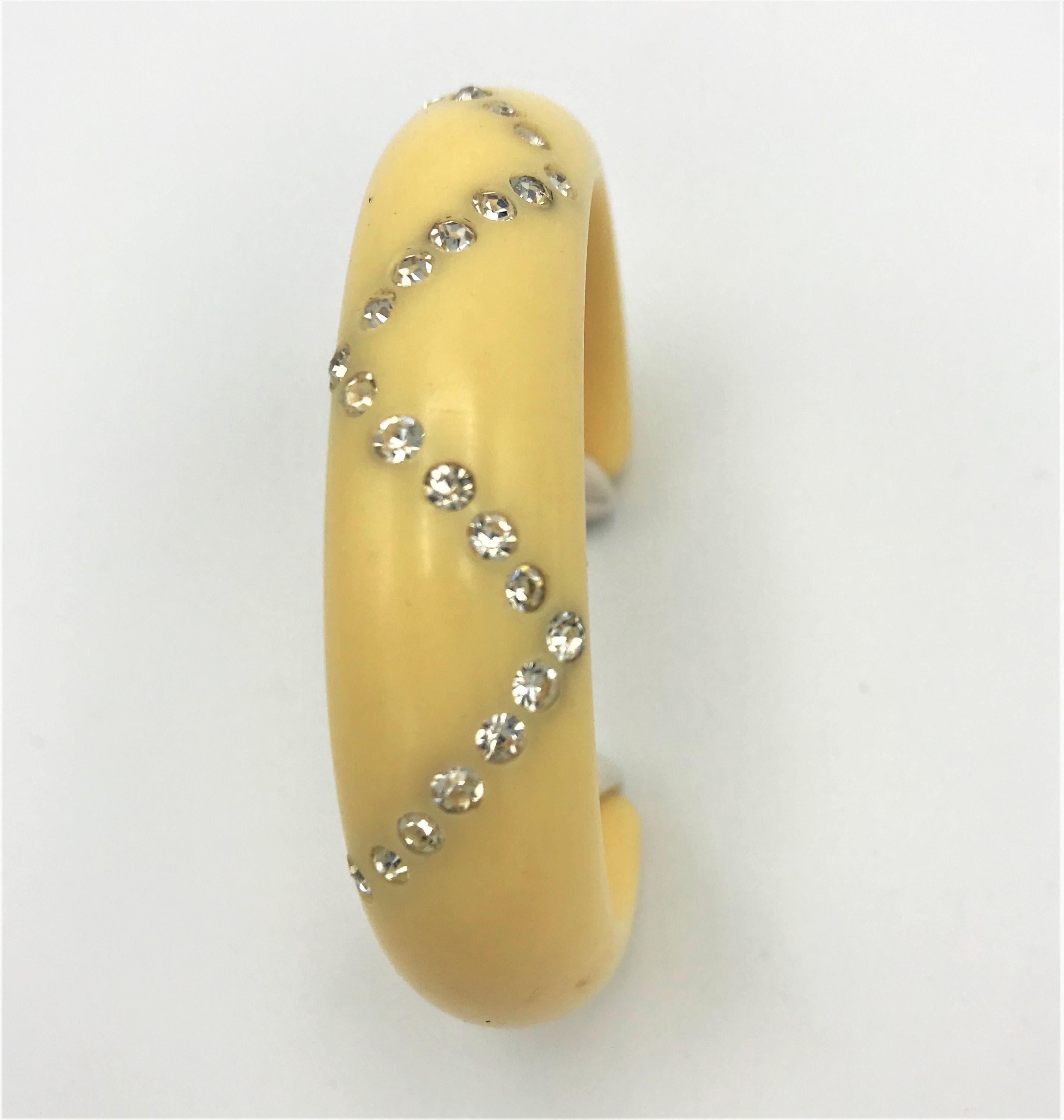 Nice Bakelite ivory-colored open bangle set with clear rhinestones .
Measurement: Width inside 2 cm, outside 2,5 cm. Inside width from opening to opening 13 cm +
3 cm . Diameter of the oval 6 cm. 
Good condition and a very nice bangle. 