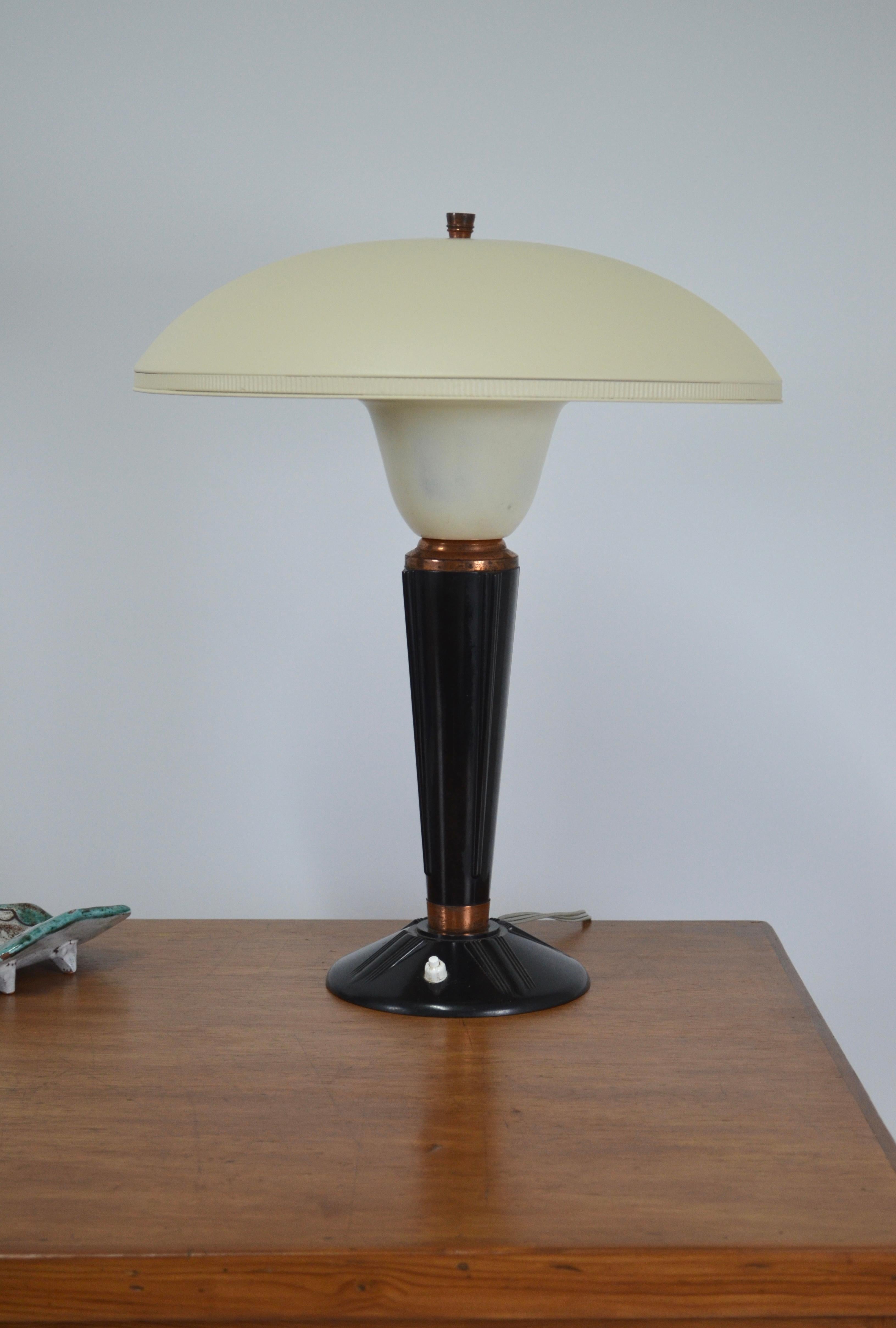 Model 320 lamp from Jumo, France, 1940s
Its body is made of bakelite (ancestor of plastic) with copper rings.
The reflector is made of ivory white color metal. The paint does not appear to be original.
Nice proportions 
Particularly elegant art deco