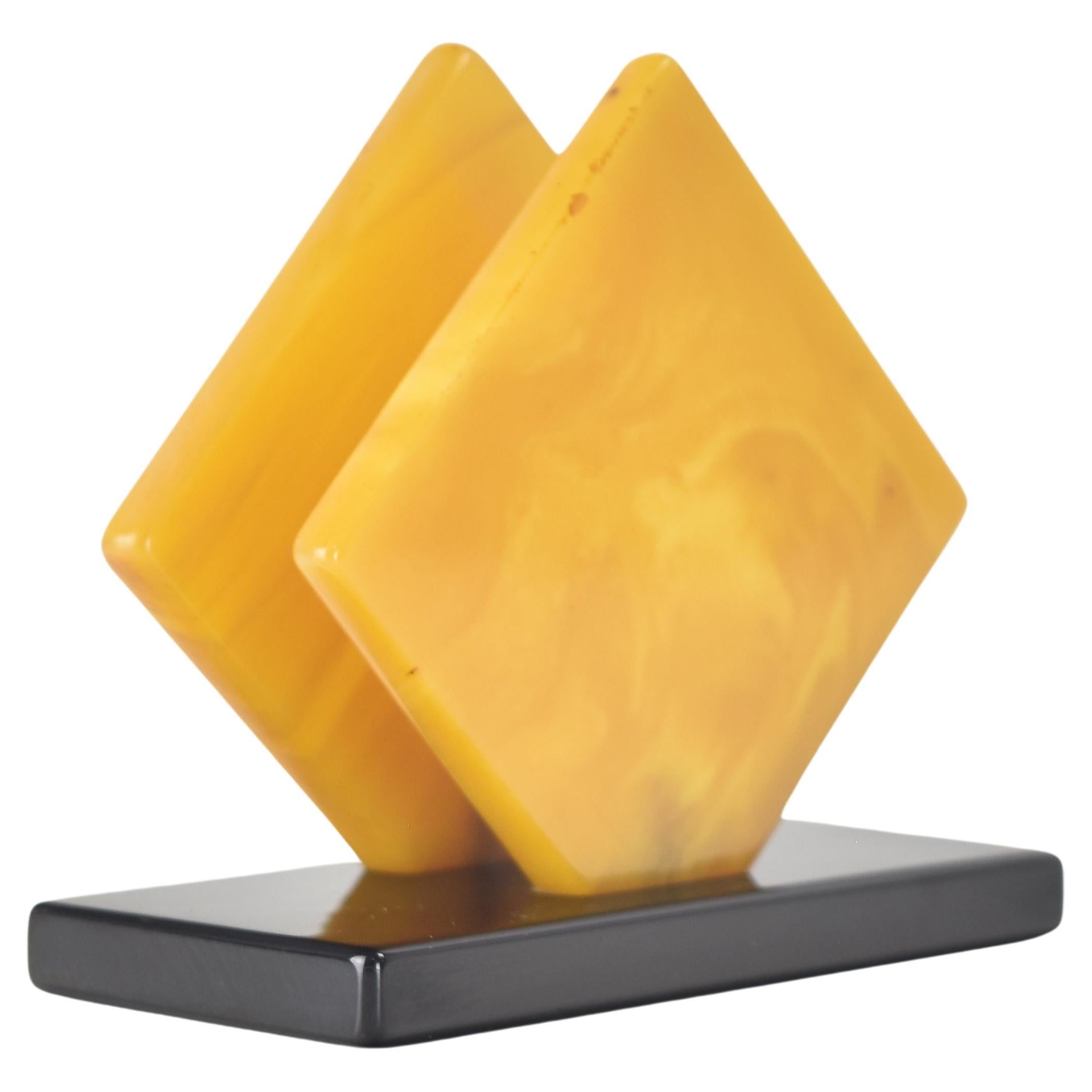 The Art Deco and Bauhaus eras were marked by a fascination with geometric shapes and clean lines, and this is reflected in the design of this cubist letter stand or napkin holders that were made from polished, marbled butterscotch bakelite with a