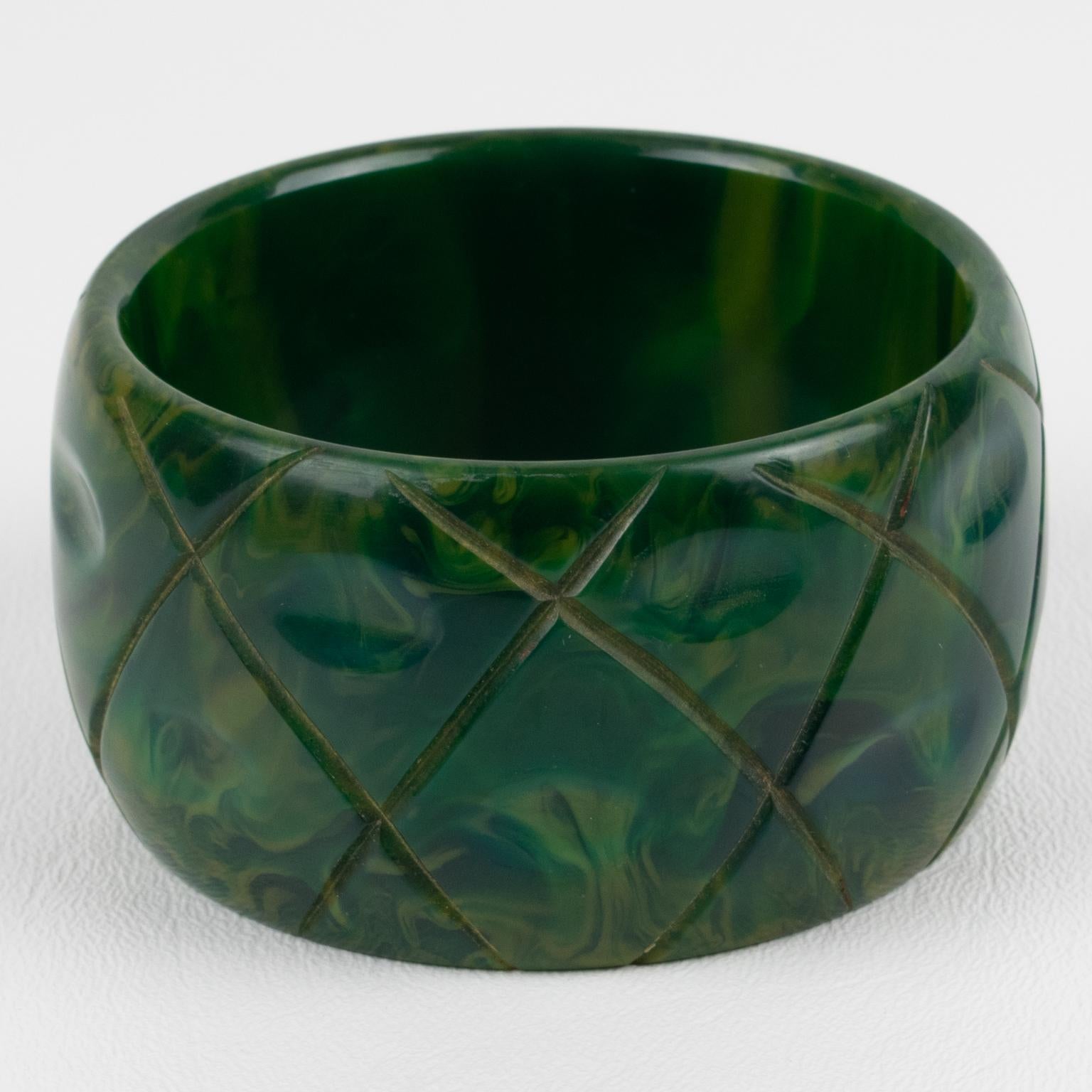 This is a gorgeous green blue-moon marble Bakelite carved bracelet bangle. It features a chunky oversized domed shape with a geometric carving design all around. The color is an intense green-blue tone with milky and light yellow cloudy swirling.