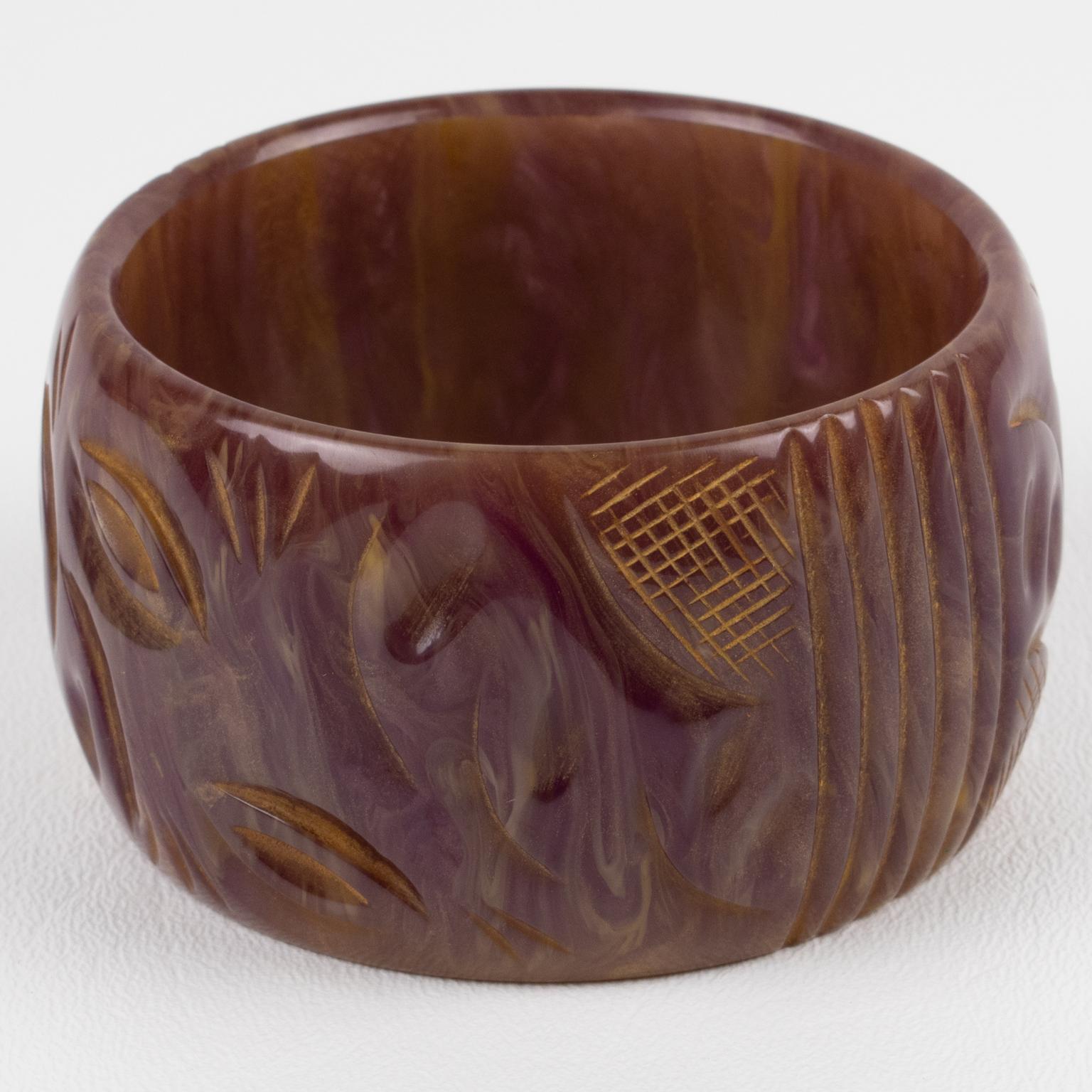 This is a superb purple stardust marble Bakelite carved bracelet bangle. It features a chunky oversized domed shape with a geometric carving design around it. The color is an intense purple with milky swirling and gold dust inclusions.