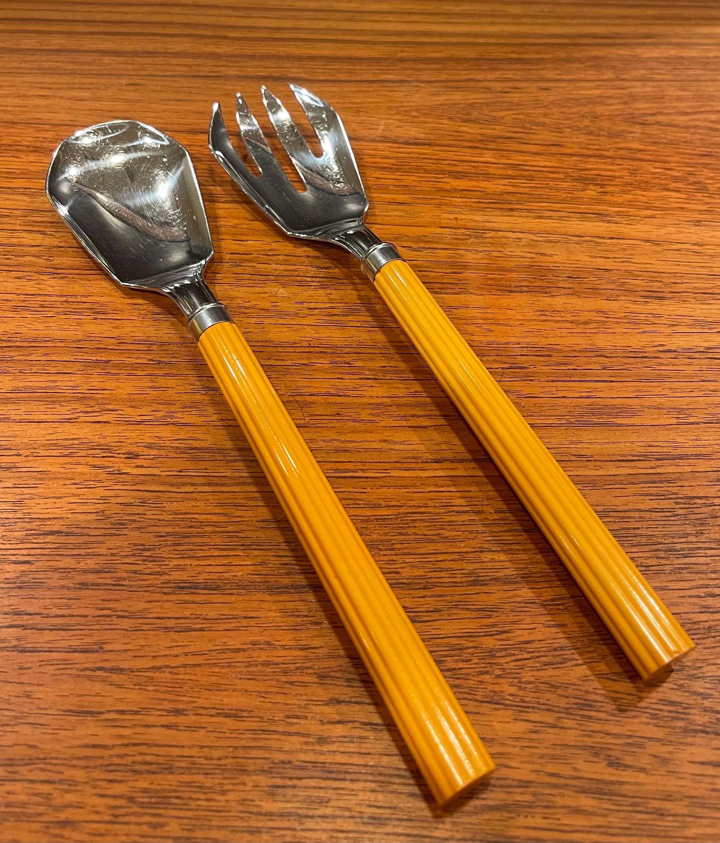 Stylish pair of butterscotch Bakelite and stainless steel Art Deco salad servers for Chase & Co., circa 1930s. The servers have ribbed handles and measure 10