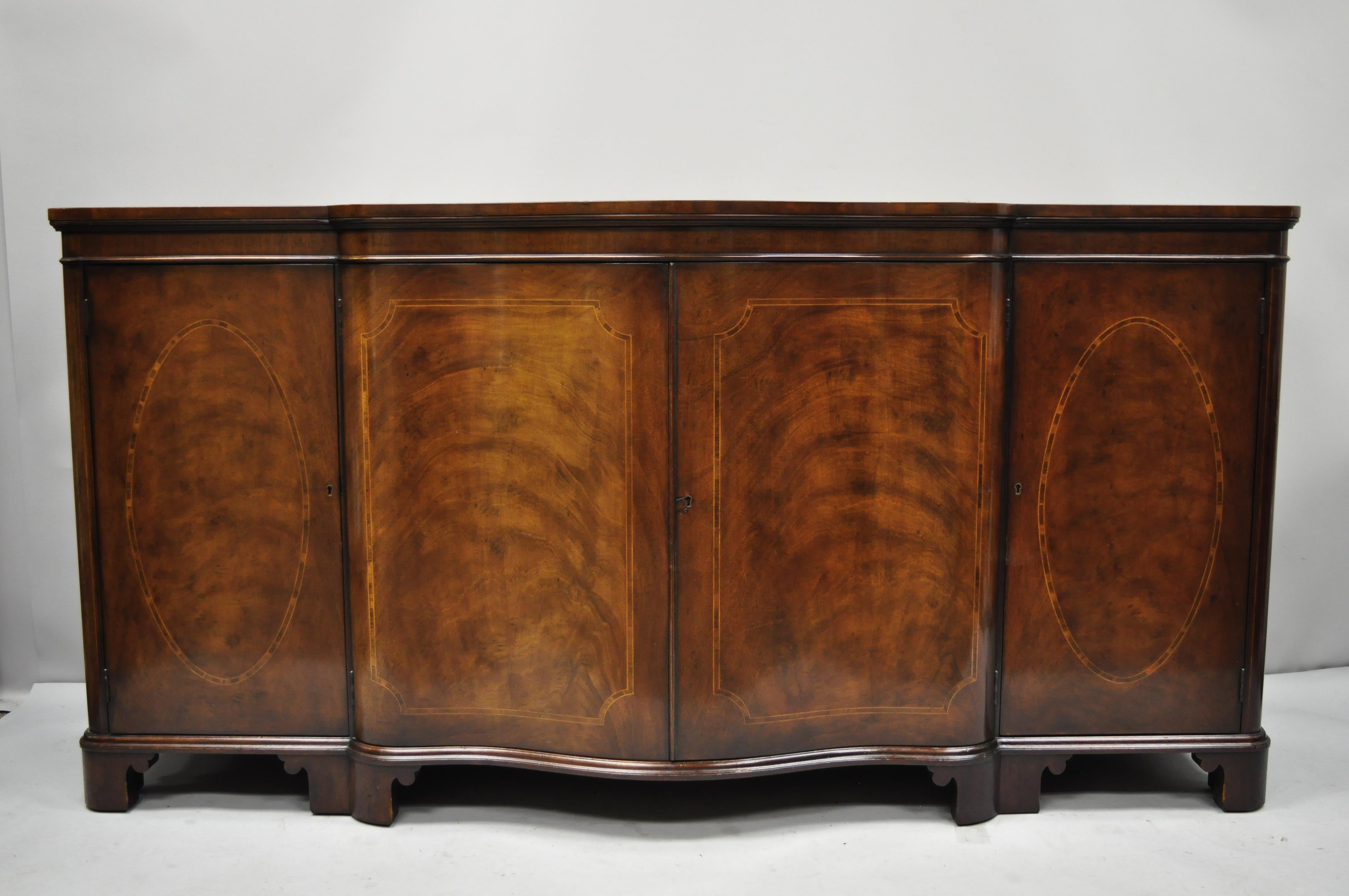 Antique flame mahogany inlaid serpentine sideboard buffet by Baker. Item features serpentine front, beautiful wood grain, 4 swing doors, original label, working lock and keys, 4 dovetailed drawers, quality American craftsmanship, great style and