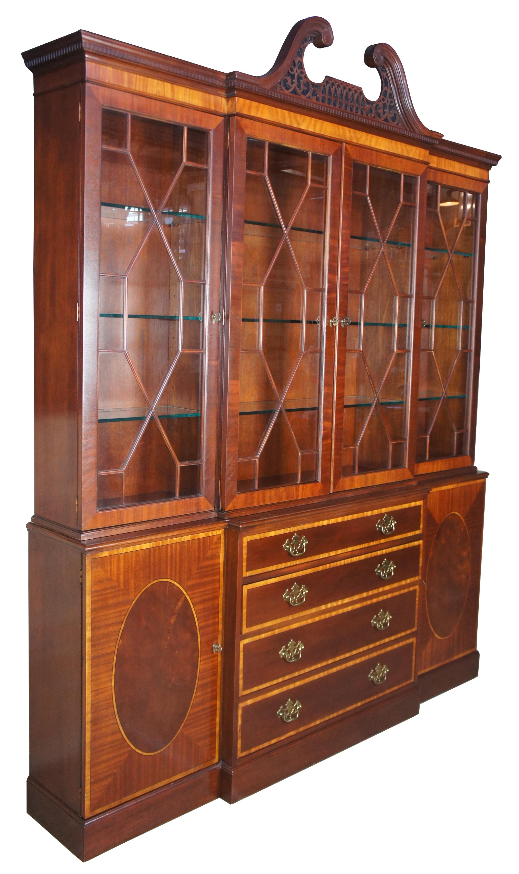 Baker banded mahogany English Chippendale style breakfront China display cabinet

Baker Furniture banded mahogany breakfront, circa 1980s. Features Chippendale styling with fretwork over the doors and along the pierced open pediment crown.