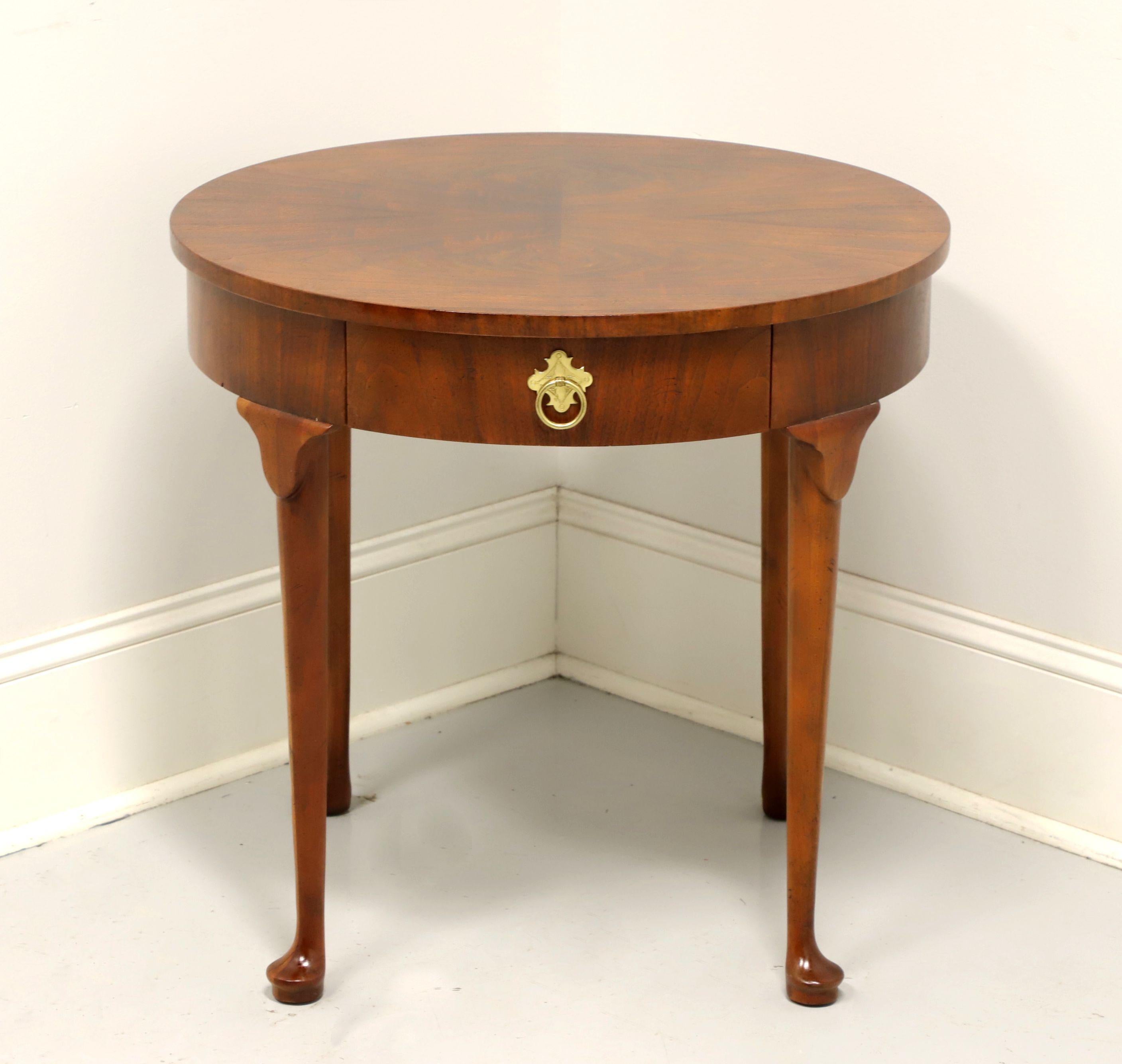 A Georgian style round accent table by Baker Furniture for high end furniture dealer, Colony Furniture of Charlotte, North Carolina, USA, under their private label in the late 20th Century. Walnut with a bookmatched burl walnut top, brass hardware,